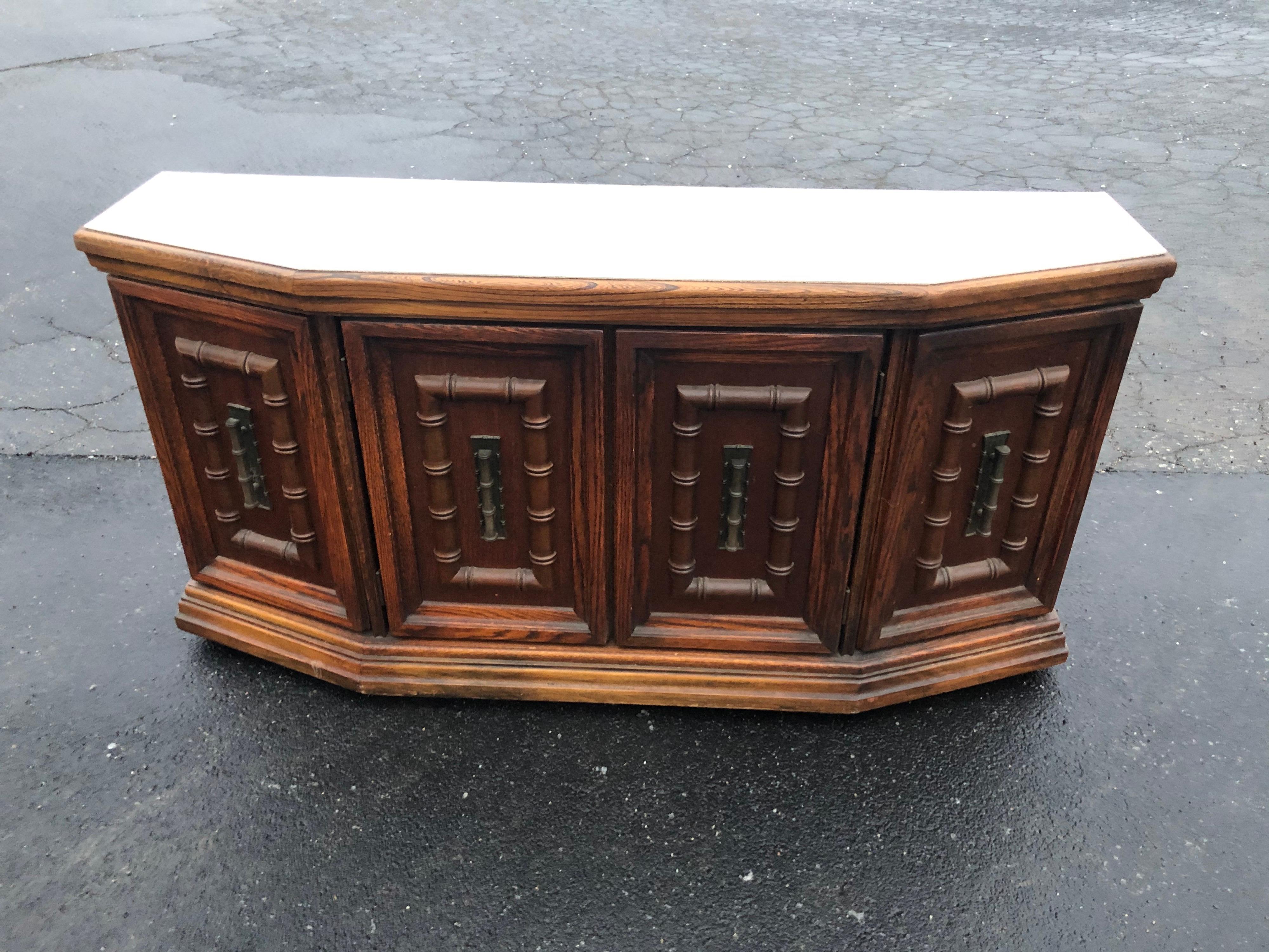 Mid Century faux bamboo credenza. Carved solid oak construction throughtout with a white laminate top for easy serving. Chunky metal hardware. Matching dining set with table and four chairs have already sold. Use as is or lacquer with a high gloss