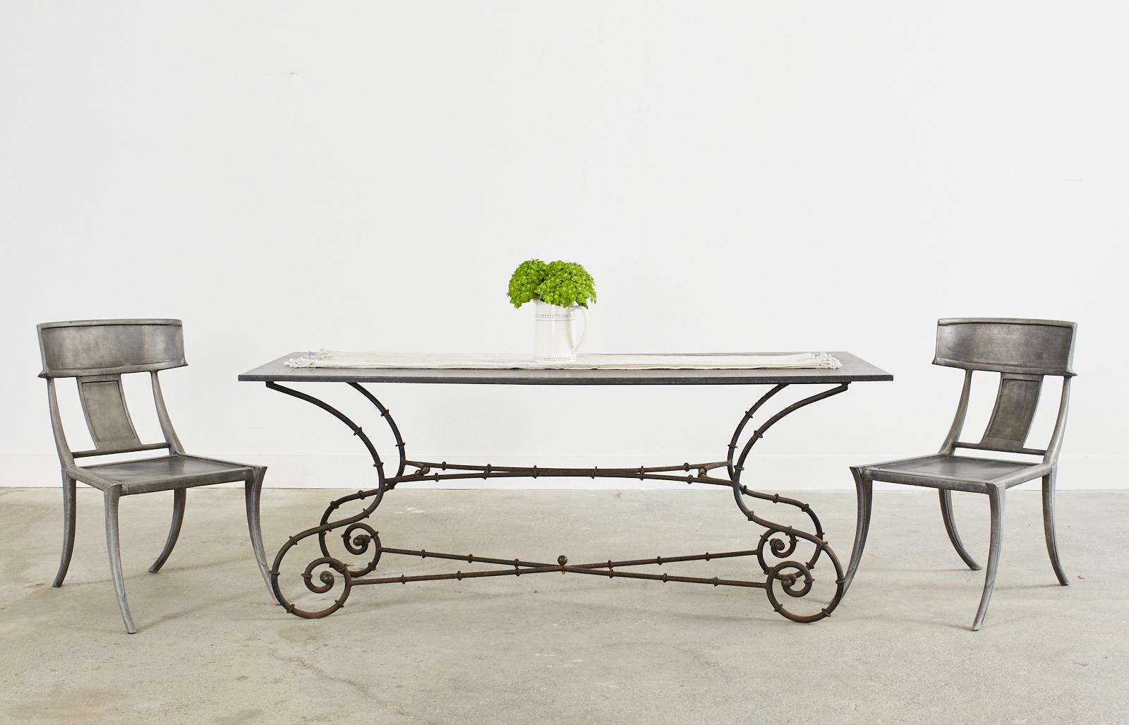 Amazing mid-century modern faux bamboo iron patio and garden dining table featuring a rare black slate top. The dramatic sinuous design is constructed from thick wrought iron having gracefully scrolled leg ends with a pair of bronze ball finials and