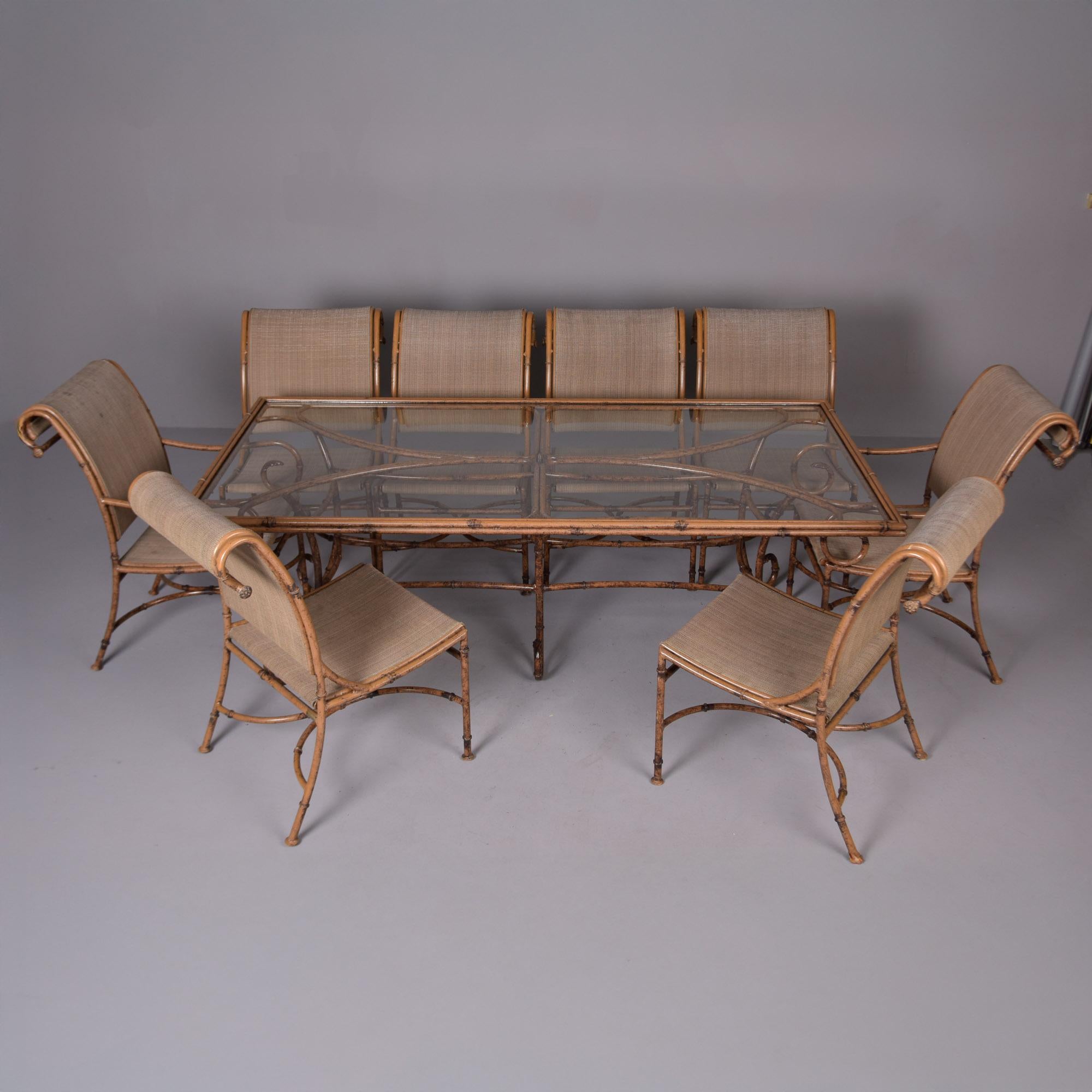 Trouvée en France, cette table en métal et en verre avec huit chaises date des années 1970. La table et les chaises à armature métallique présentent un style en faux bambou. Il y a deux fauteuils à accoudoirs ou capitaines et six fauteuils