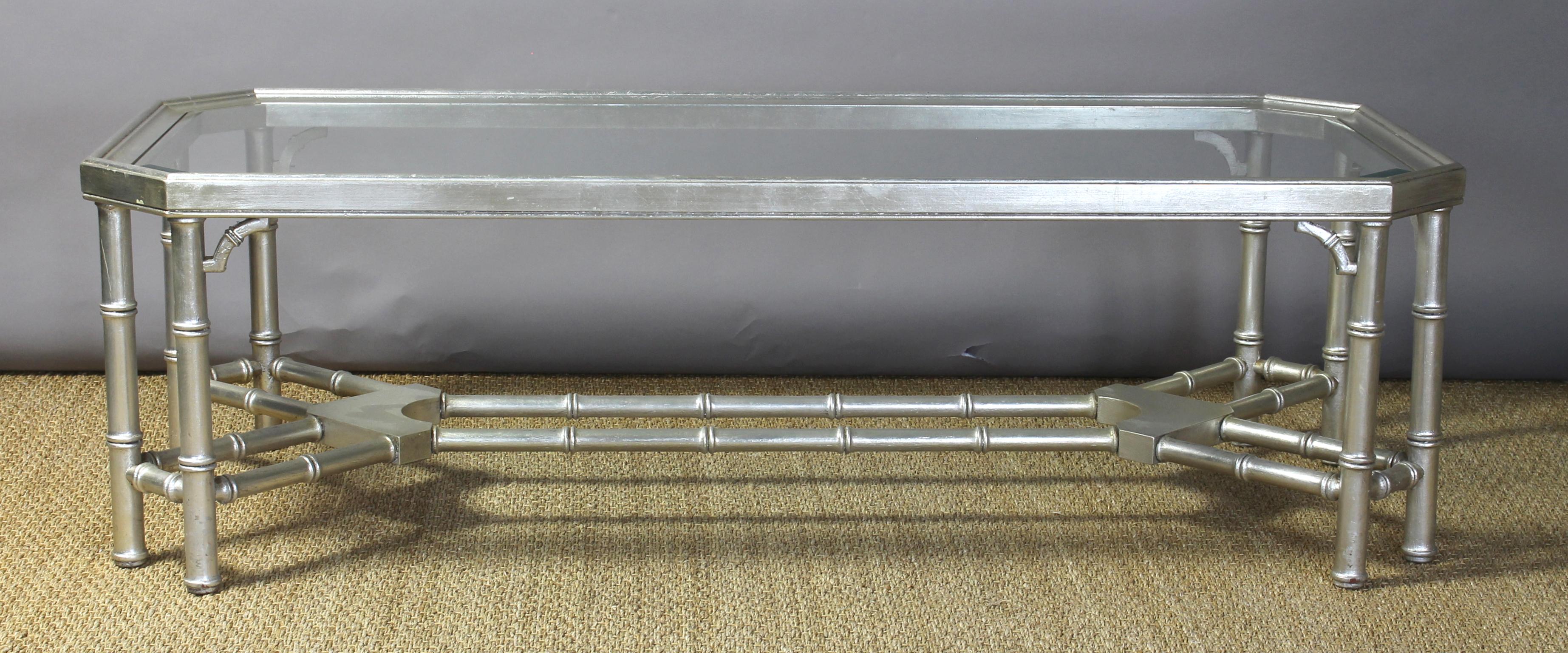 An elegant mid-20th century glass and faux bamboo cocktail table of fairly large rectangular scale, finished in a slightly distressed silver leaf.