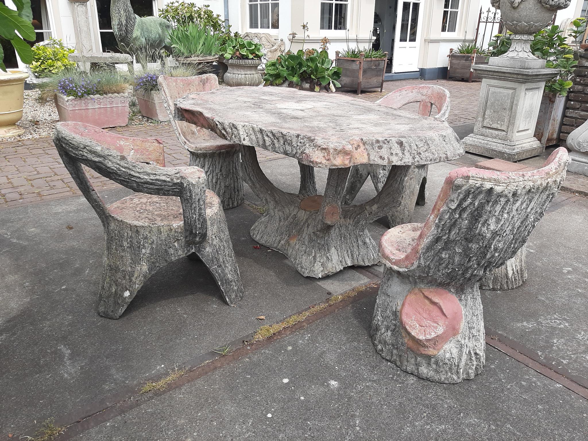 A midcentury faux bois stone garden table and chairs. Faux Bois (false wood) refers to the artistic imitation of wood and wood grains in various media. This rustic concrete garden set is composed of four chairs (of which two have armrests) a stool