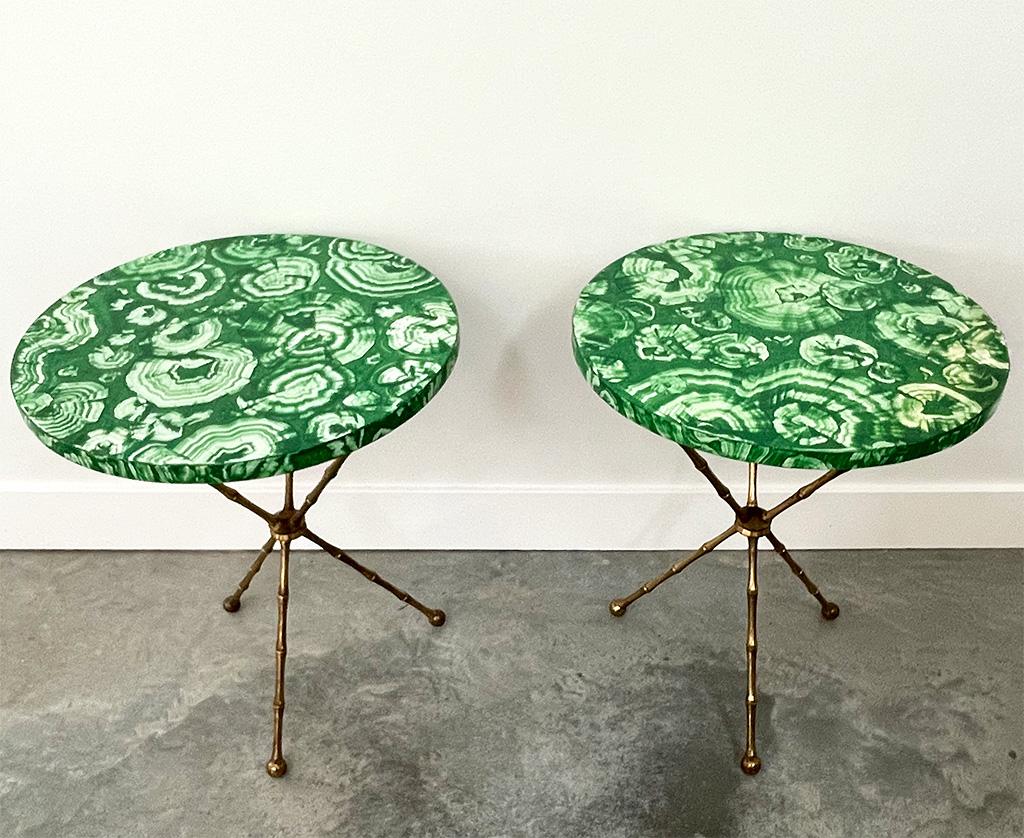 Beautifully painted on wood tops, these Faux Malachite tables are an iconic design from the Hollywood Regency Period and very Mid-Century in design. It is rare to find a pair together and in such great shape. The brass tripod bases have a bamboo