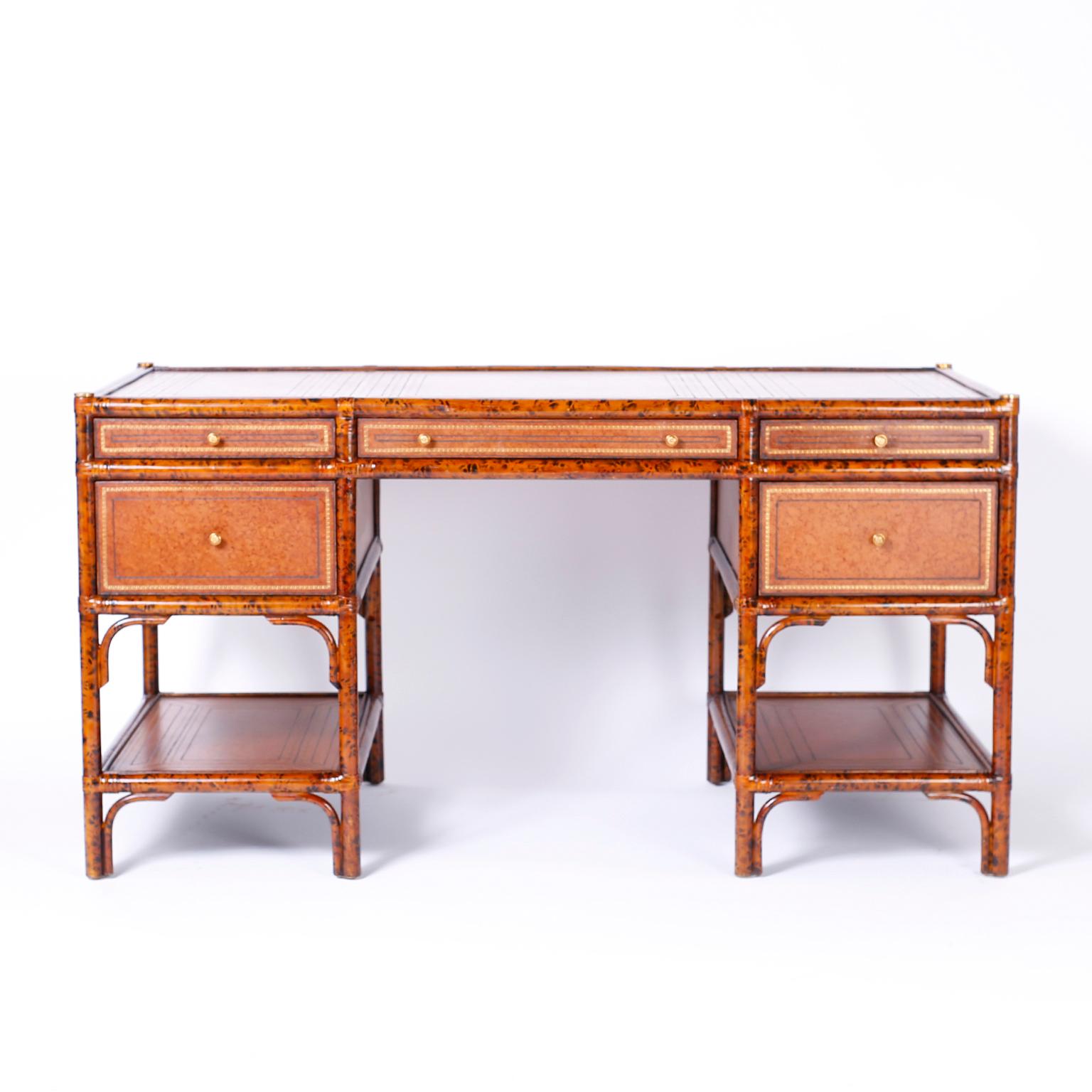 Midcentury kneehole five-drawer desk with a faux tortoise frame featuring a paneled and tooled leather top, drawer fronts, sides and lower tiers. The desk has a finished back and is signed Maitland-Smith in a drawer.