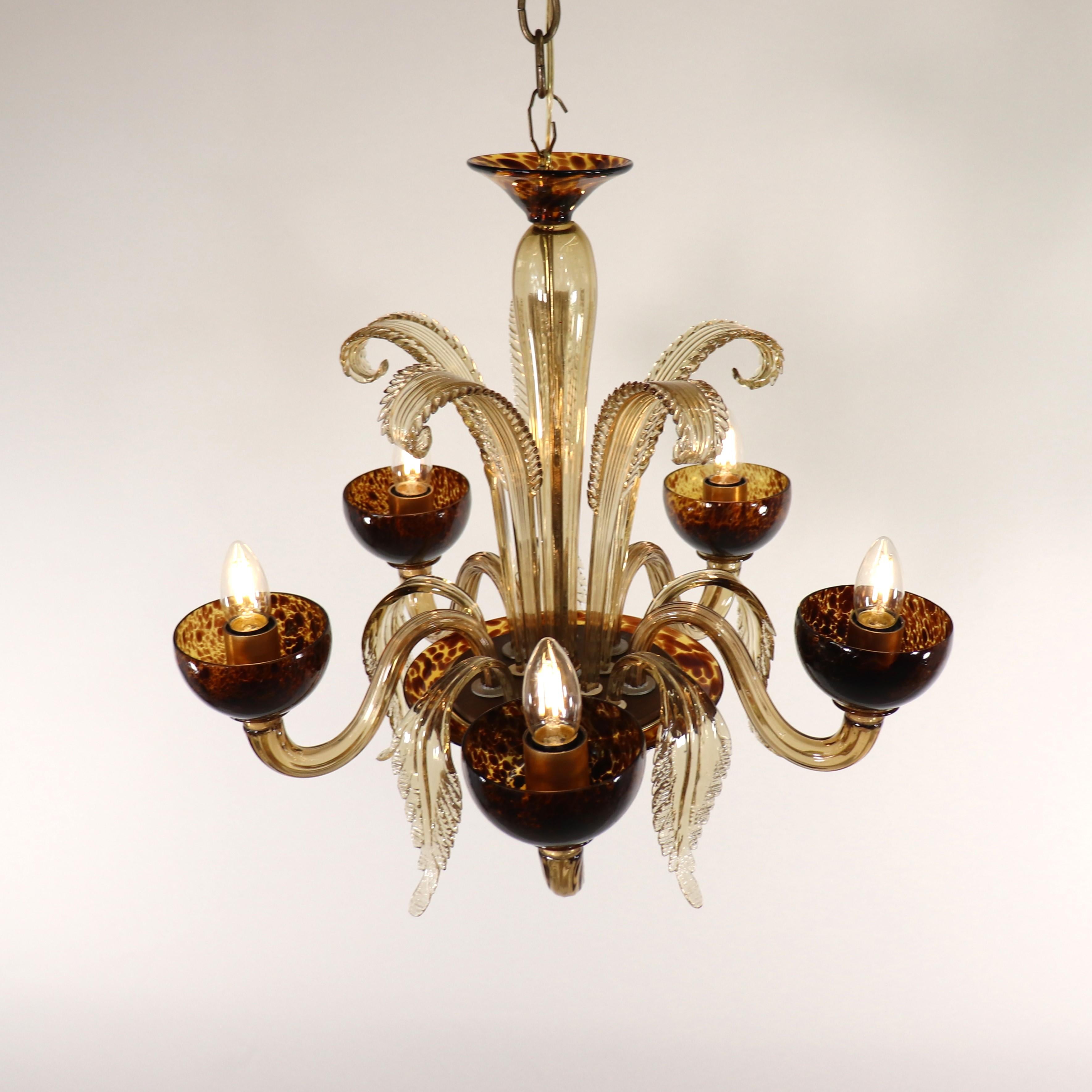 This exquisitely handcrafted two-toned mid-century Murano chandelier has five undulating arms emerging from the central bowl. Glass leaves embellish this chandelier, blooming up and over the bottom from the bulbous center column. The prominent