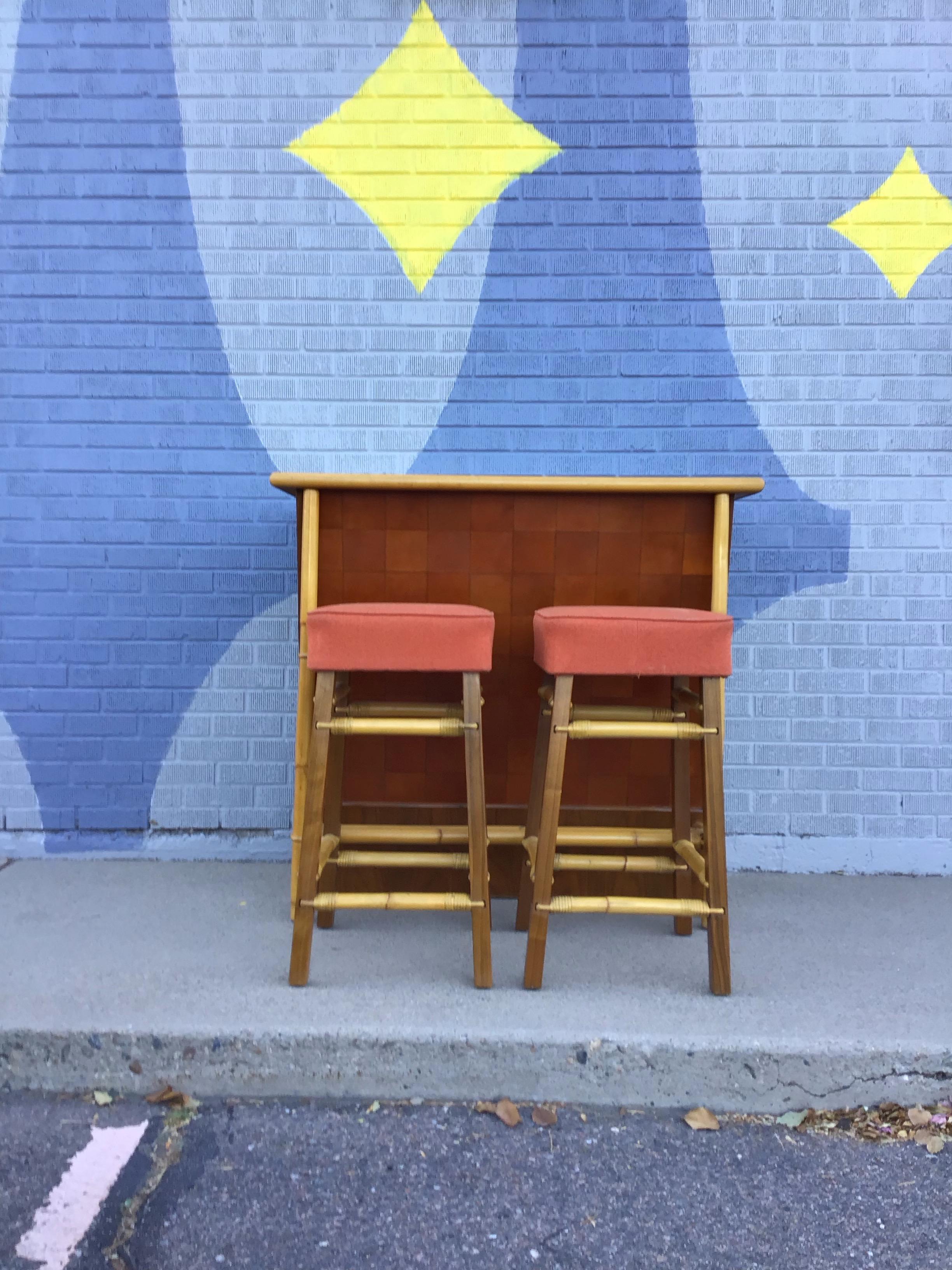 Un unico e raro set da bar di Fabrice Reed della metà del secolo scorso che presenta due sgabelli in bambù e noce con un tessuto arancione bruciato, e un bancone in bambù e noce con parte anteriore in pelle caramellata 