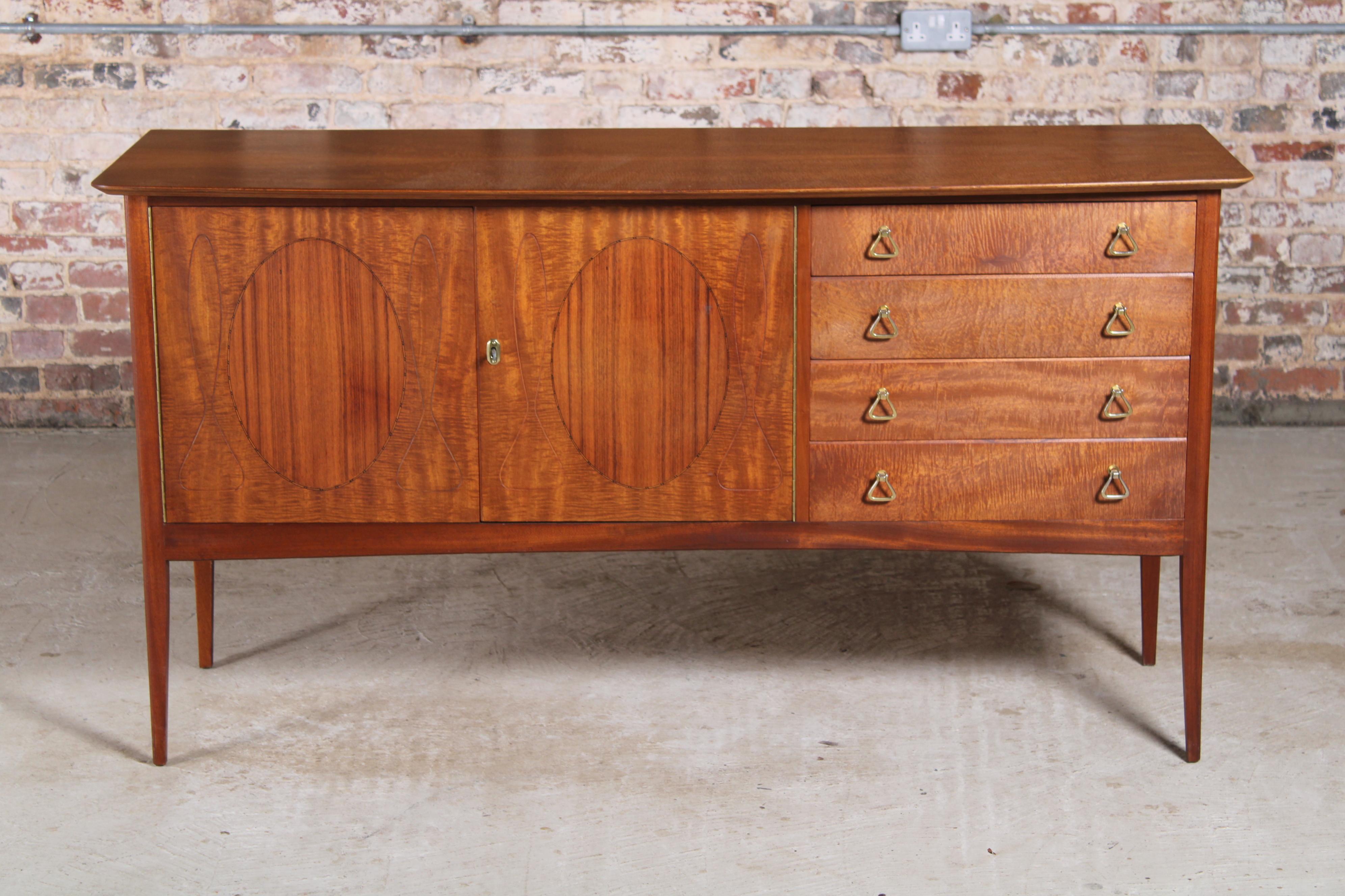 Mid Century Fiddleback Mahogany sideboard with rosewood insets by John Herbert for Younger Ltd, England. Can be found in 1957 Younger catalogue. A cabinet section and 4 drawers with felt lined cutlery drawer on top.

Dimensions: 160 W x 53 D x 86