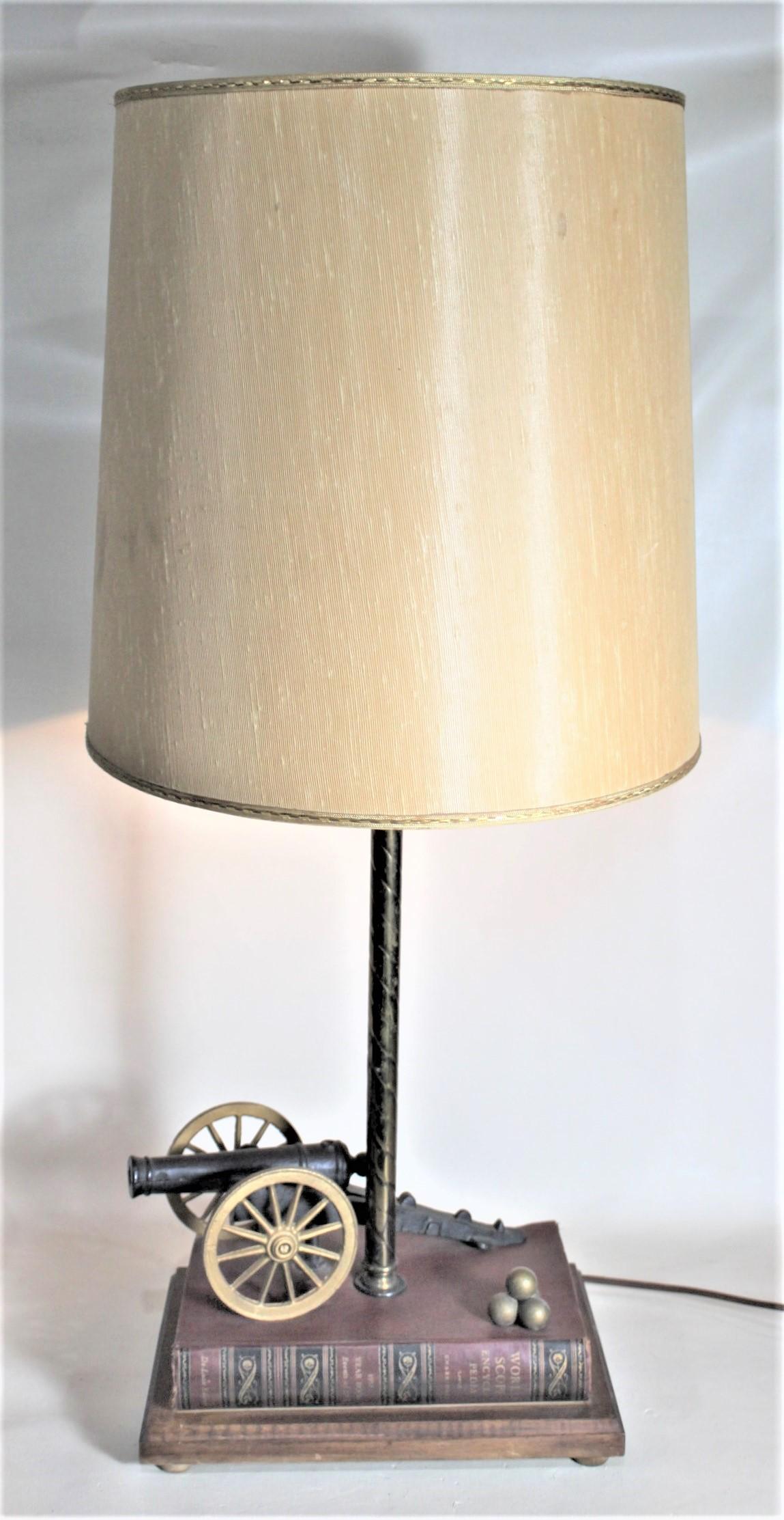 This very unique and functional table lamp is unsigned, but presumed to have been homemade in Canada in approximately 1965 in the period midcentury style. The lamp features a figural cast iron canon and leather bound book with cast canon balls