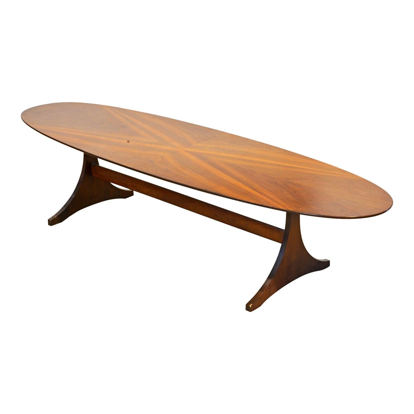 This well designed eliptical coffee table features a surf board shape beautifully figured walnut top resting on two shaped consoles connected by a long stretcher. It is indistinctly marked 