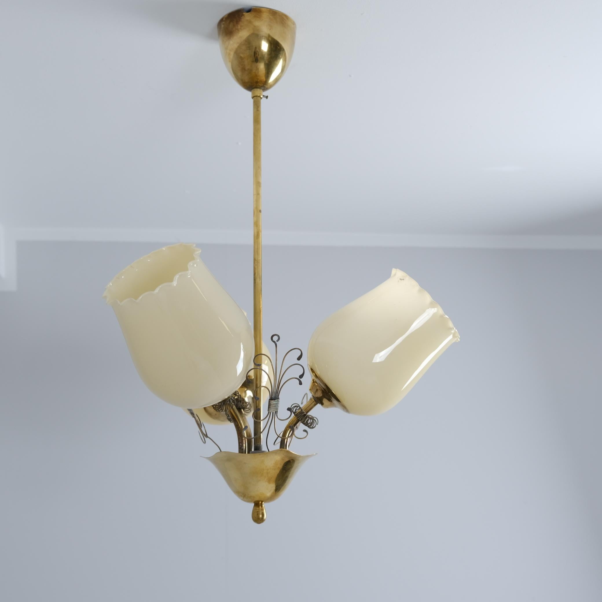 Una encantadora lámpara de techo finlandesa de los años 50 con tres pantallas de cristal beige crema, que encarna la elegante sencillez del diseño escandinavo de mediados de siglo. Aunque recuerda a las icónicas luminarias de Paavo Tynell, esta