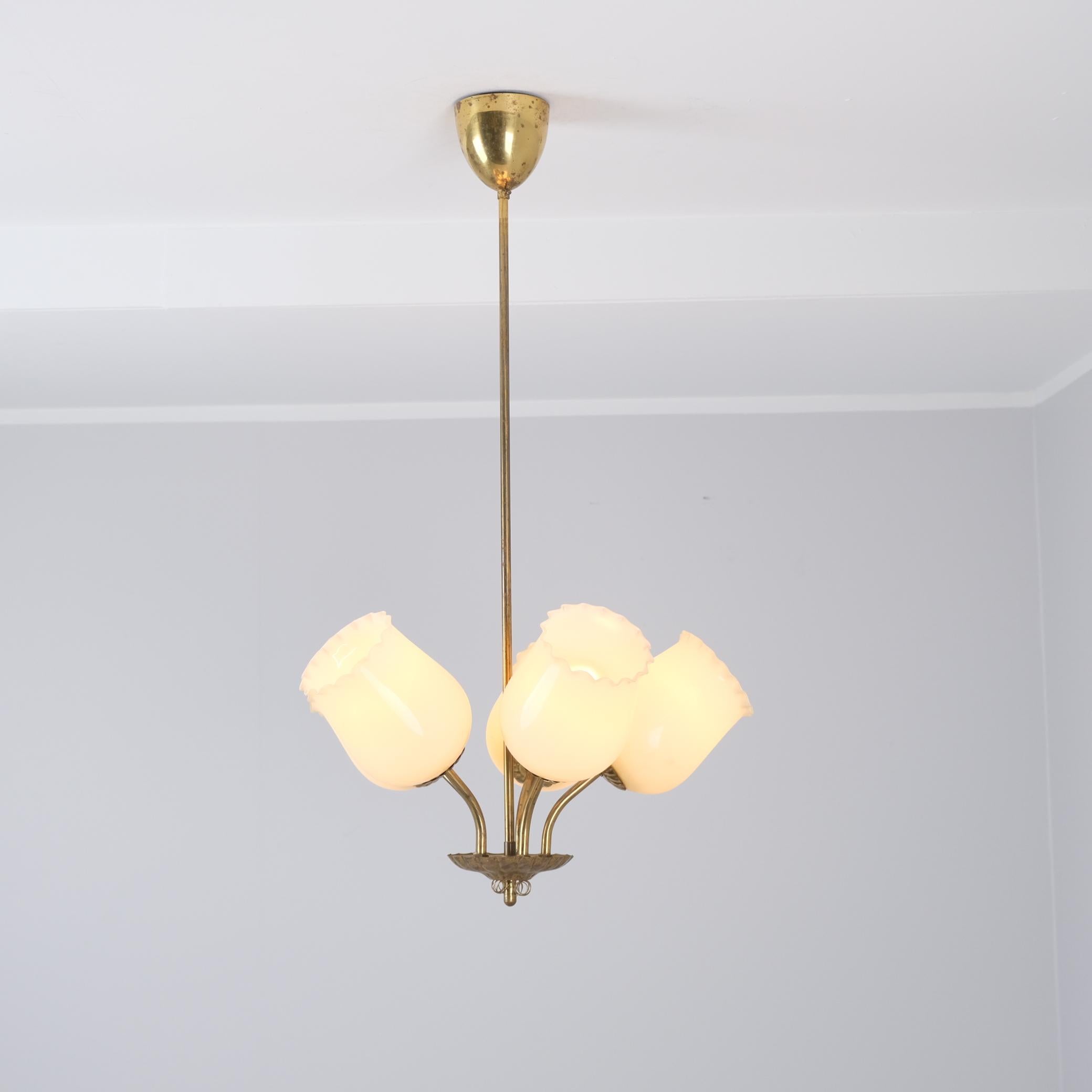 Charmant plafonnier finlandais des années 1950, doté de cinq abat-jour en verre beige crème en forme de bouton de fleur, incarnant l'élégante simplicité et l'élégance du design scandinave du milieu du siècle dernier. Tout en rappelant les luminaires