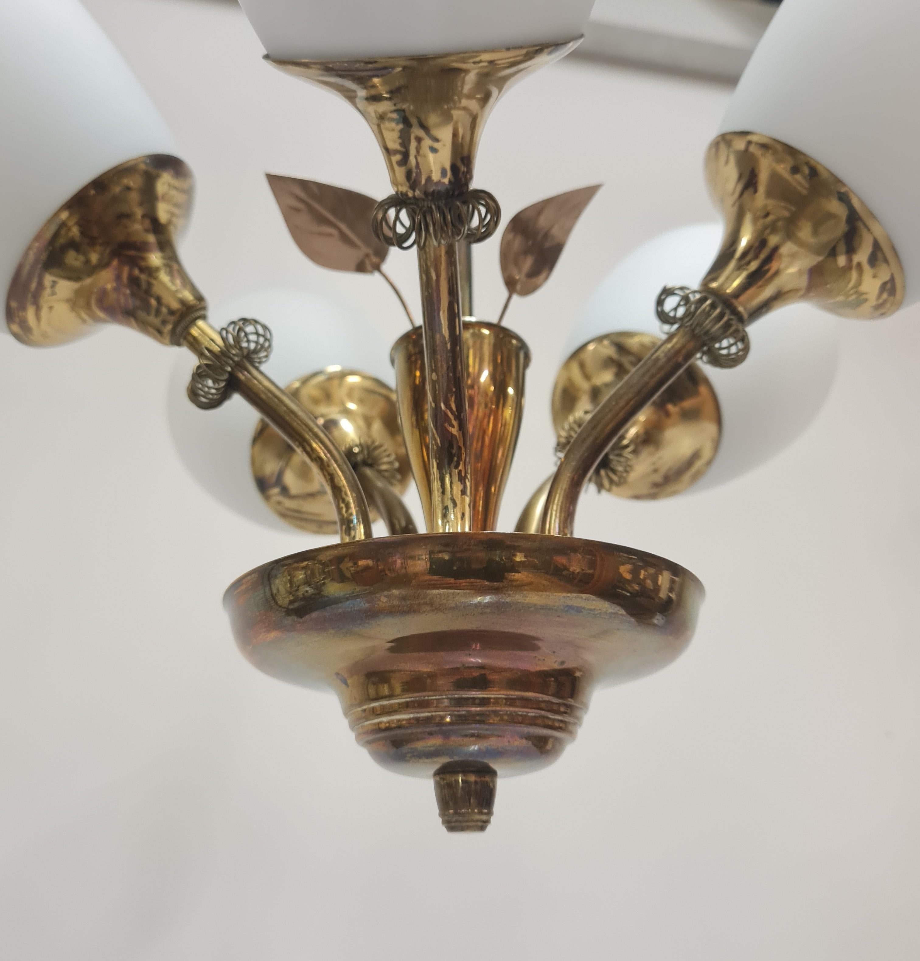 Una lampada da soffitto dal design finlandese degli anni '50 con cinque fonti di luce e decorazioni a forma di foglia. Questa lampada presenta alcune somiglianze con le lampade Paavo Tynell, ma poiché non tutti potevano permettersi le Tynell, anche