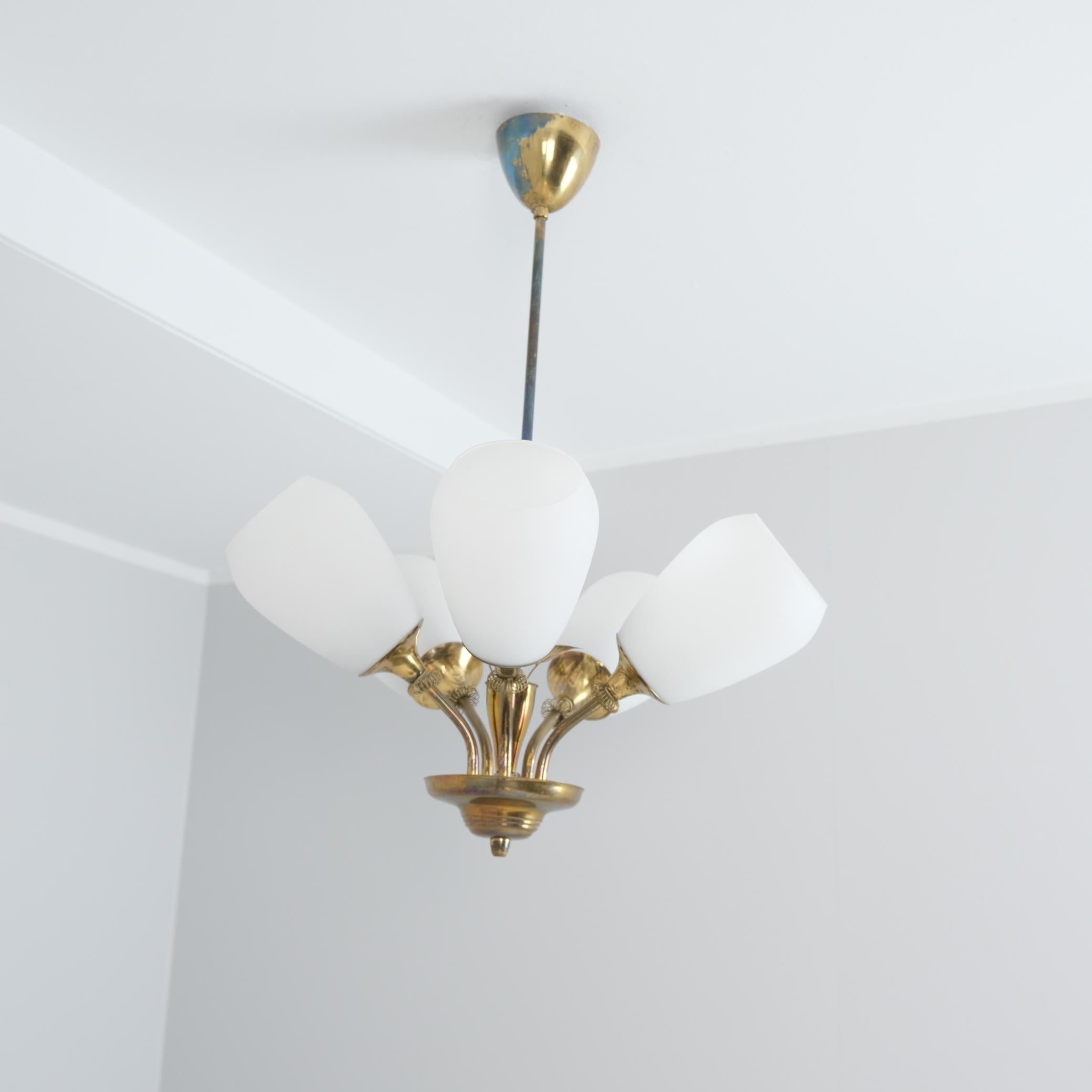 Una lampada da soffitto dal design finlandese degli anni '50 con cinque fonti di luce e decorazioni a forma di foglia. Questa lampada presenta alcune somiglianze con le lampade Paavo Tynell, ma poiché non tutti potevano permettersi le Tynell, anche