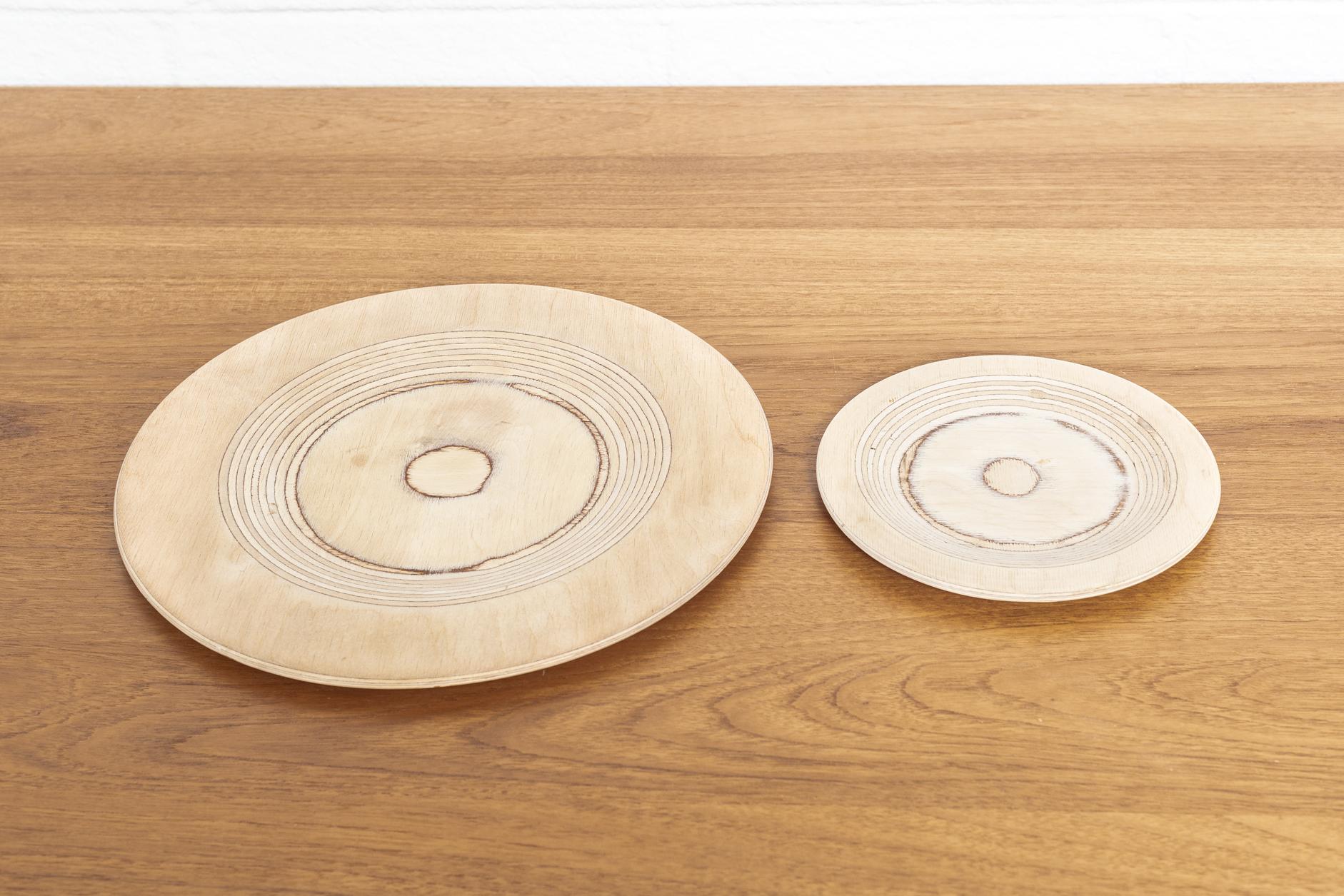 This striking pair of Mid-Century Modern wooden plates was designed by Saarinen and produced by Keuruu in Finland circa 1960. The clean, Minimalist design crafted from turned birch plywood features beautiful natural grain. The set includes 2