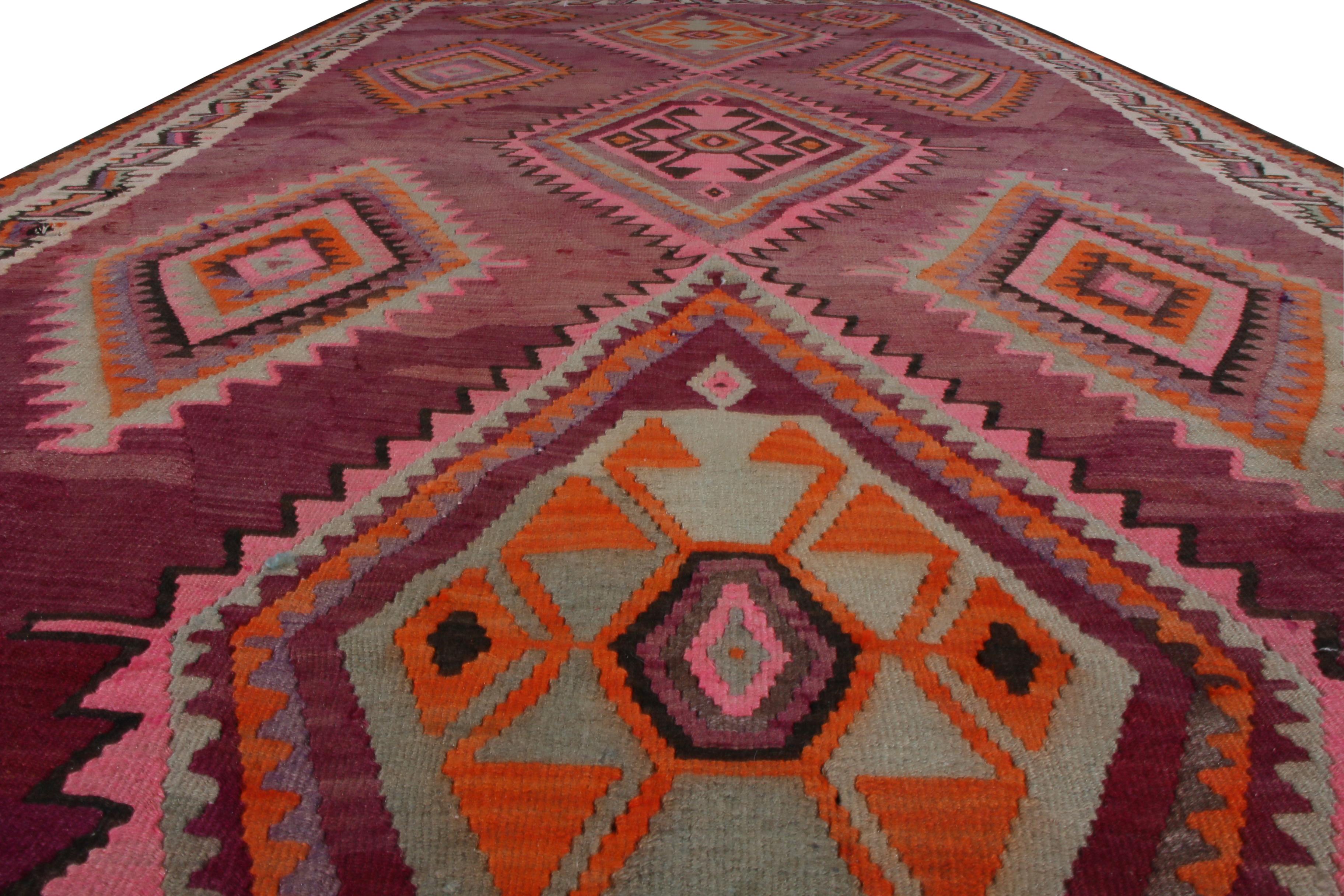 Handwoven in wool with midcentury origins circa 1950-1960, this vintage 4’10 x 9’11 Northwest Persian Kilim rug features all-over geometric tribal patterns in red, green, orange, pink, and black. The traditional medallion patterns of this vintage