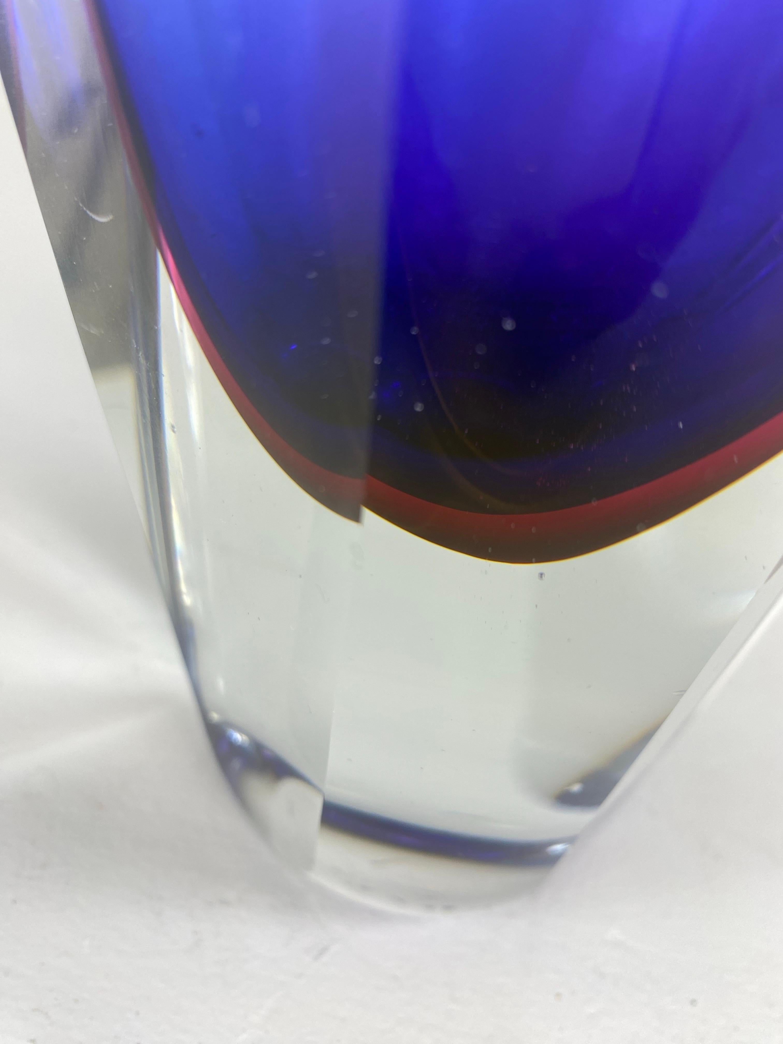 Il s'agit d'un vase en verre d'art à facettes de Murano, soufflé à la main, datant du milieu du siècle dernier. Ce vase est d'un bleu royal profond avec un contour rouge incrusté dans une classe claire. Ce vase est facetté sur quatre côtés. Ce vase