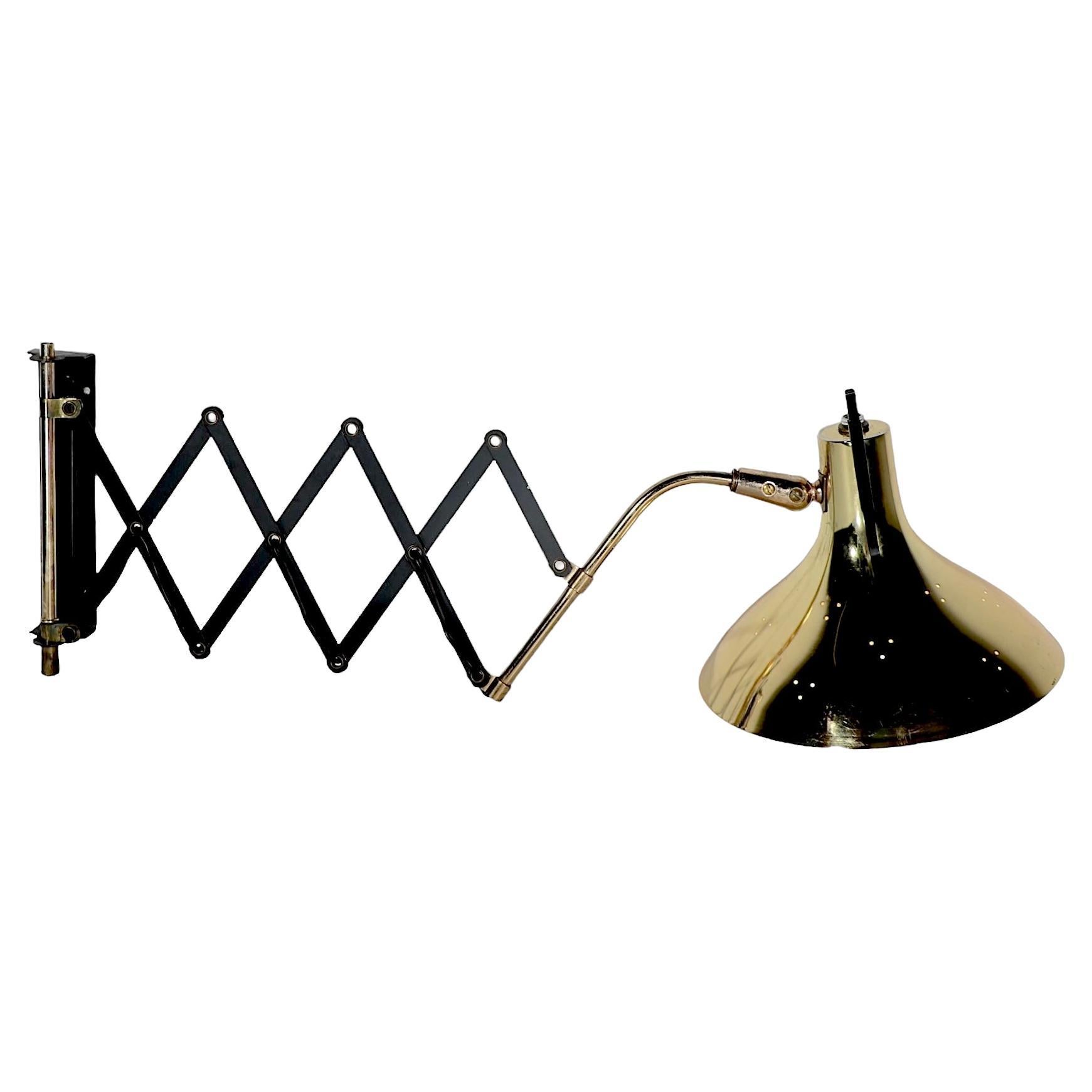 Mid Century architectural  flex arm wall mount pin up sconce, attributed to Gerald Thurston, for Lightolier. 
The sconce features a bell form shade constructed of brass, with decorative hole piercing, and a black iron handle to direct the light. The