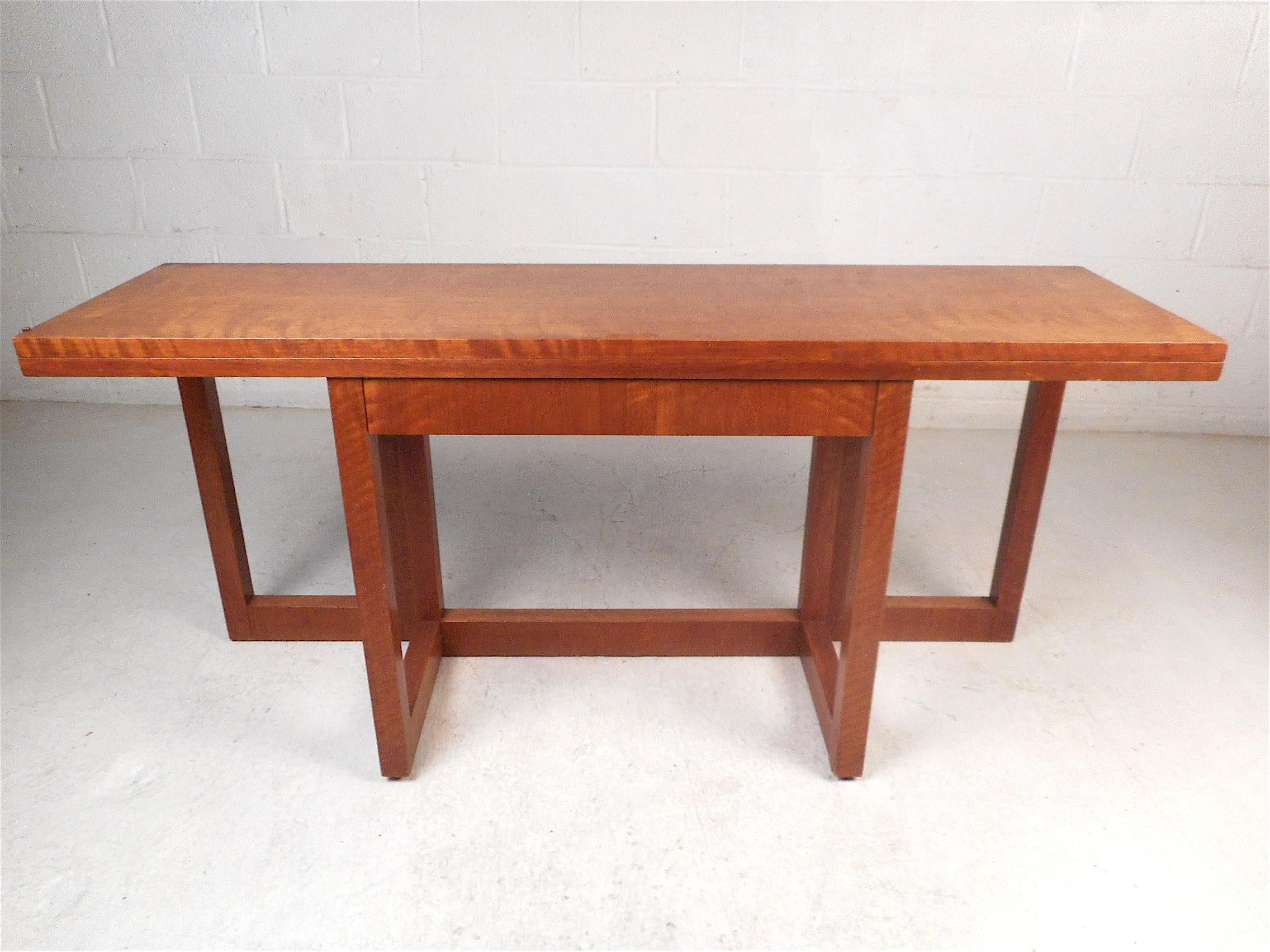 Unusual midcentury table made by Founders Furniture Co. Utilizing the piece's flip-top table and gate leg supports, the table expands from a console table into a spacious dining table. Use as a hall-table in daily living and as a dining table when