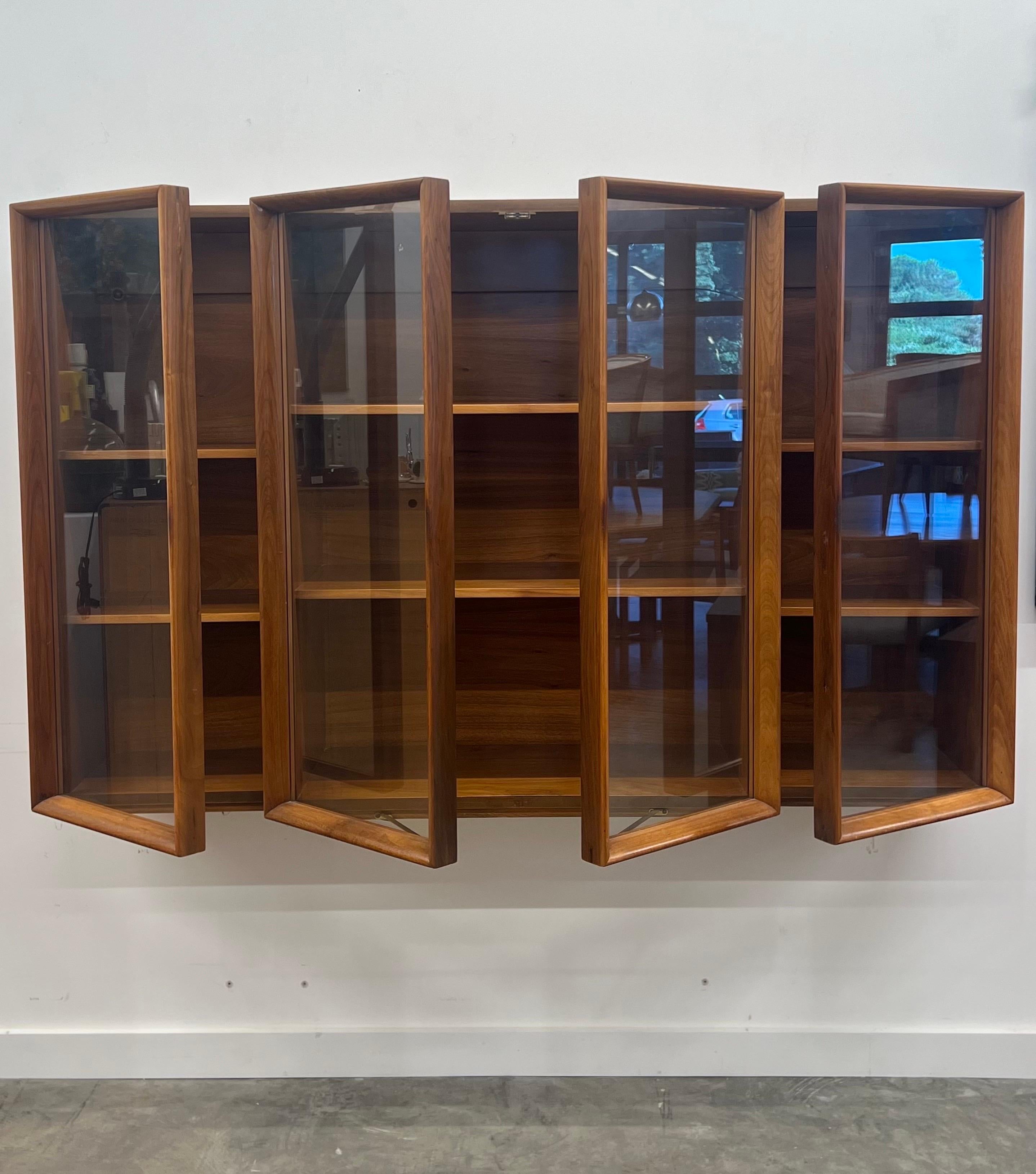 Mobile curio a muro di United Furniture Corporation, risalente alla metà del secolo scorso. Un design geometrico molto bello realizzato in legno di noce. Questo pezzo è caratterizzato da quattro porte rettangolari: due centrali e una su ciascun