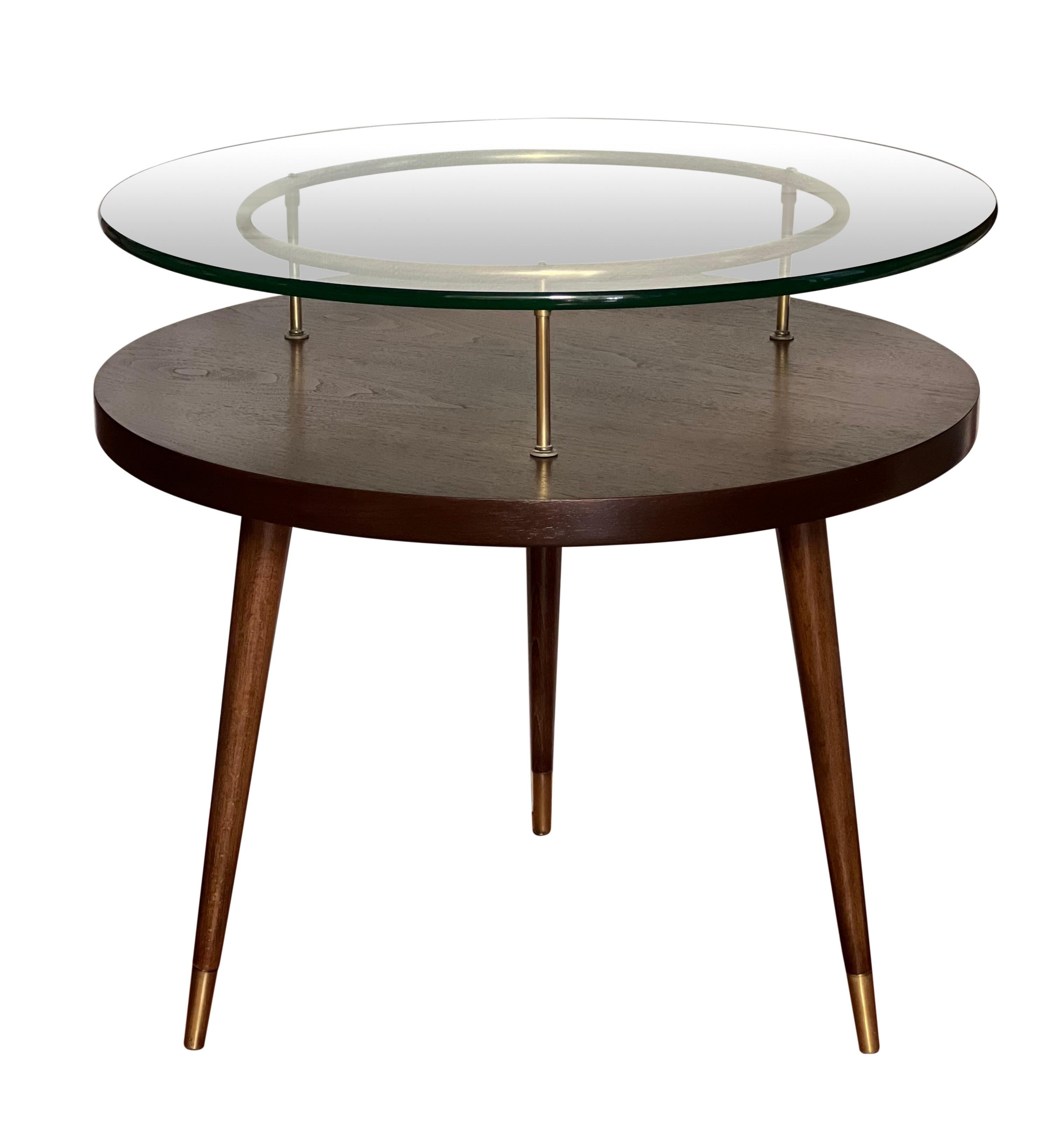 Wonderful 1950's floating glass side table by James-Philip Company, refinished.

The sturdy table has a two tier design with thick floating glass supported by a circular brass frame. Features classic mid century styling with three brass capped,