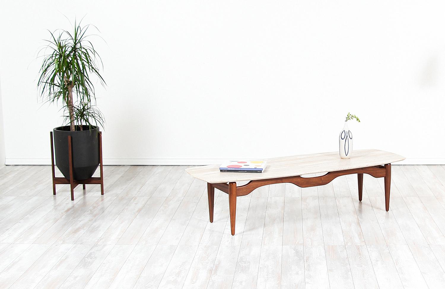 Beautiful Mid-Century Modern coffee table designed and manufactured in the United States, circa 1960s. This elegant table features a solid structured walnut wood base with four tapered legs and uniquely carved stretchers that support a new custom