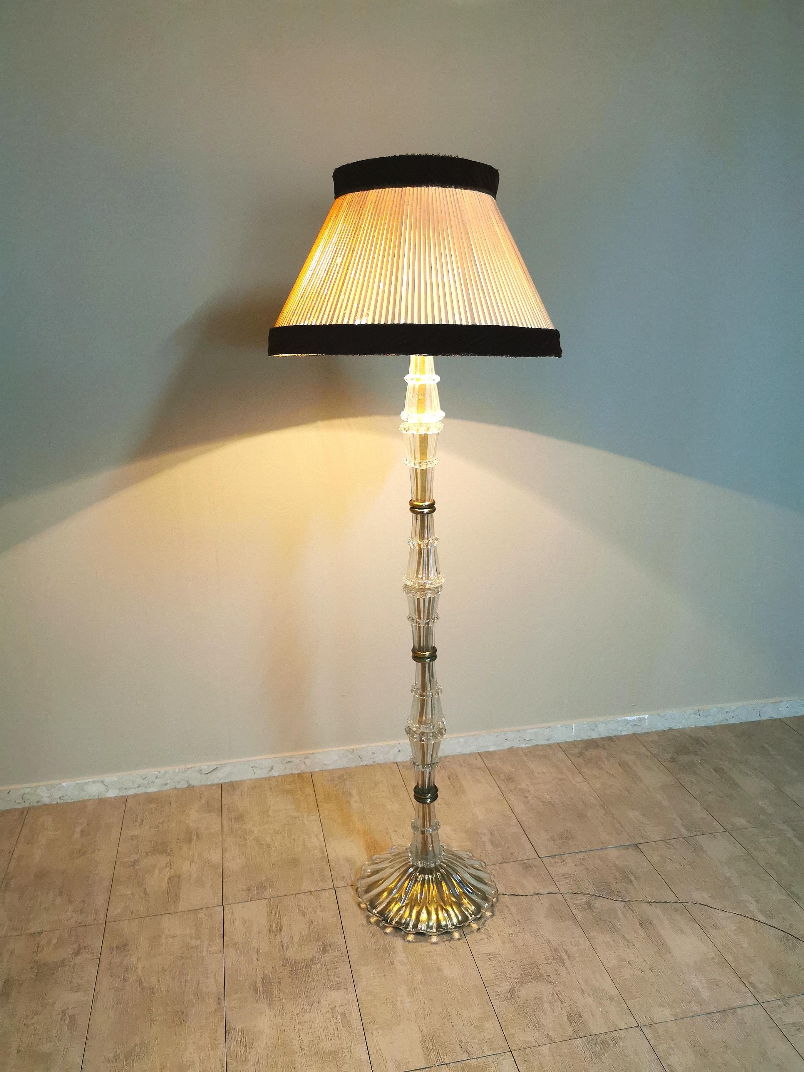 Elegant floor lamp attributable to Ercole Barovier produced in Italy in the 1940s. The lamp is characterized by a long stem made entirely of transparent Murano glass as well as the base with brass accessories and diffuser in silk and burgundy velvet.