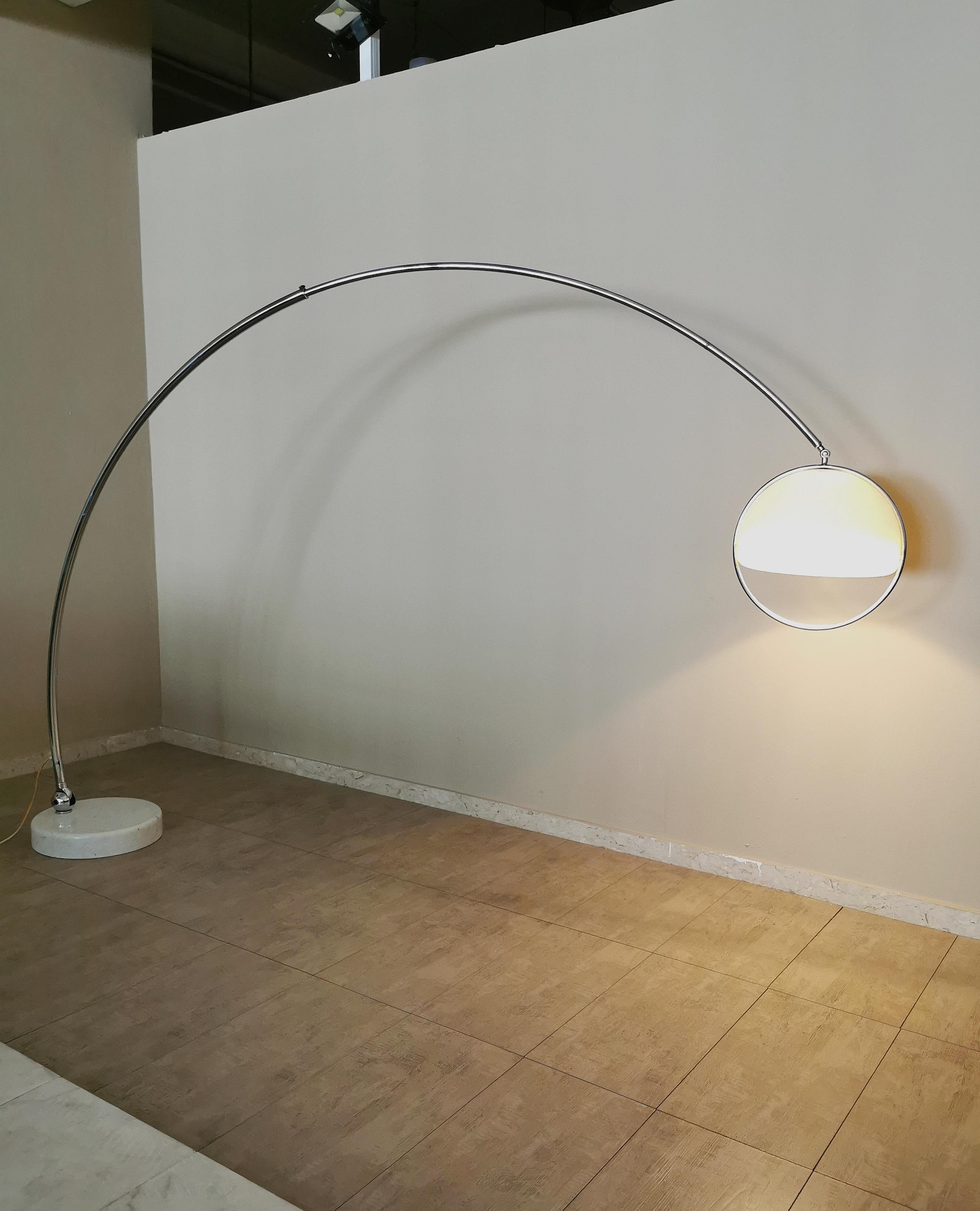Lámpara de pie de arco, rara y de gran tamaño, diseñada por el diseñador italiano Goffredo Reggiani. La lámpara tiene una base redonda de mármol blanco, con un orificio para alojar la varilla metálica cromada giratoria y extensible. Termina con un