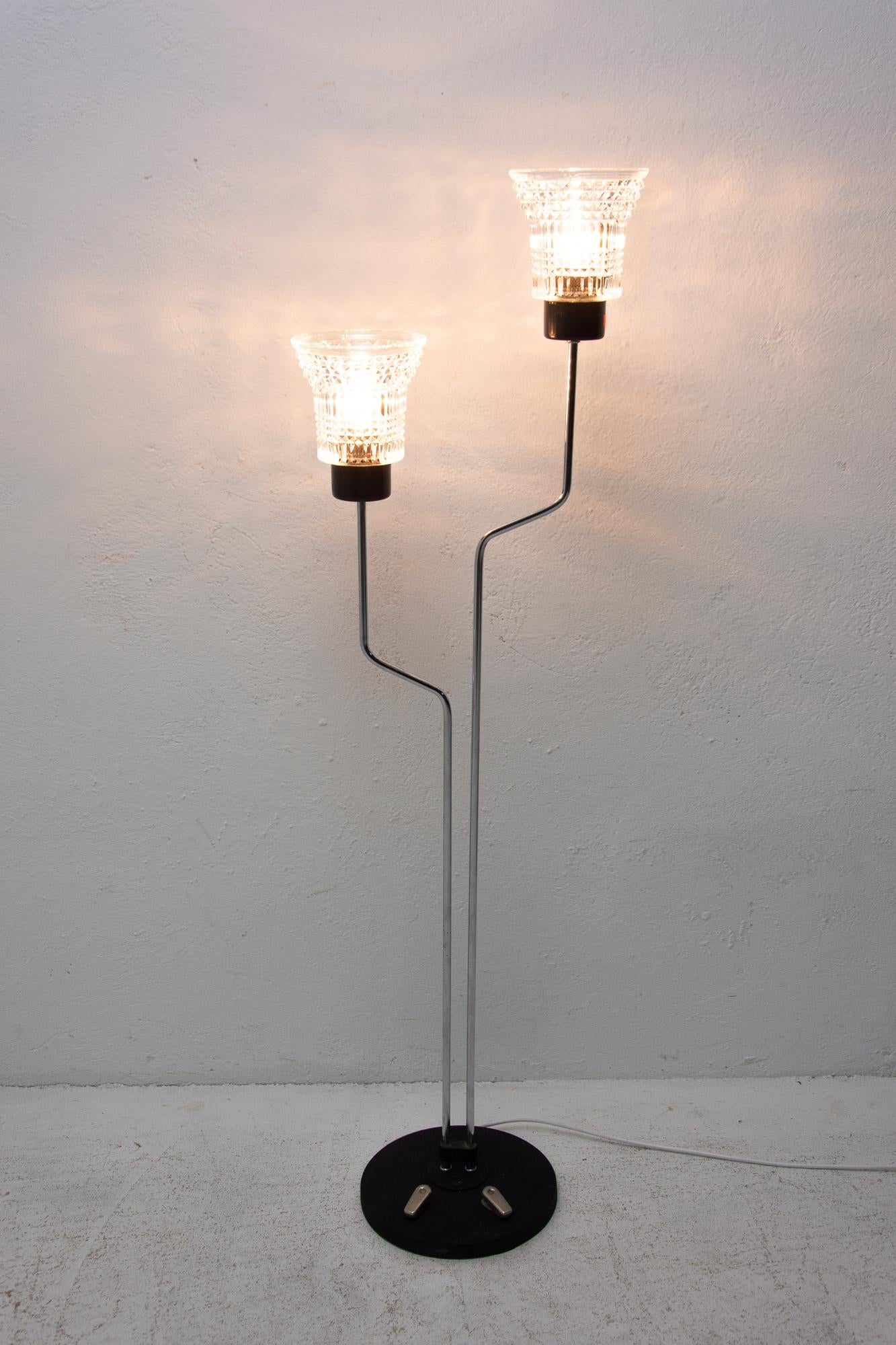 Midcentury floor lamp, made in the former Czechoslovakia in the 1960s. Chrome-plated curved construction. Two staggered chromed stems ending in the glass shades. A round wooden base with two foot switches. In very good vintage condition. New