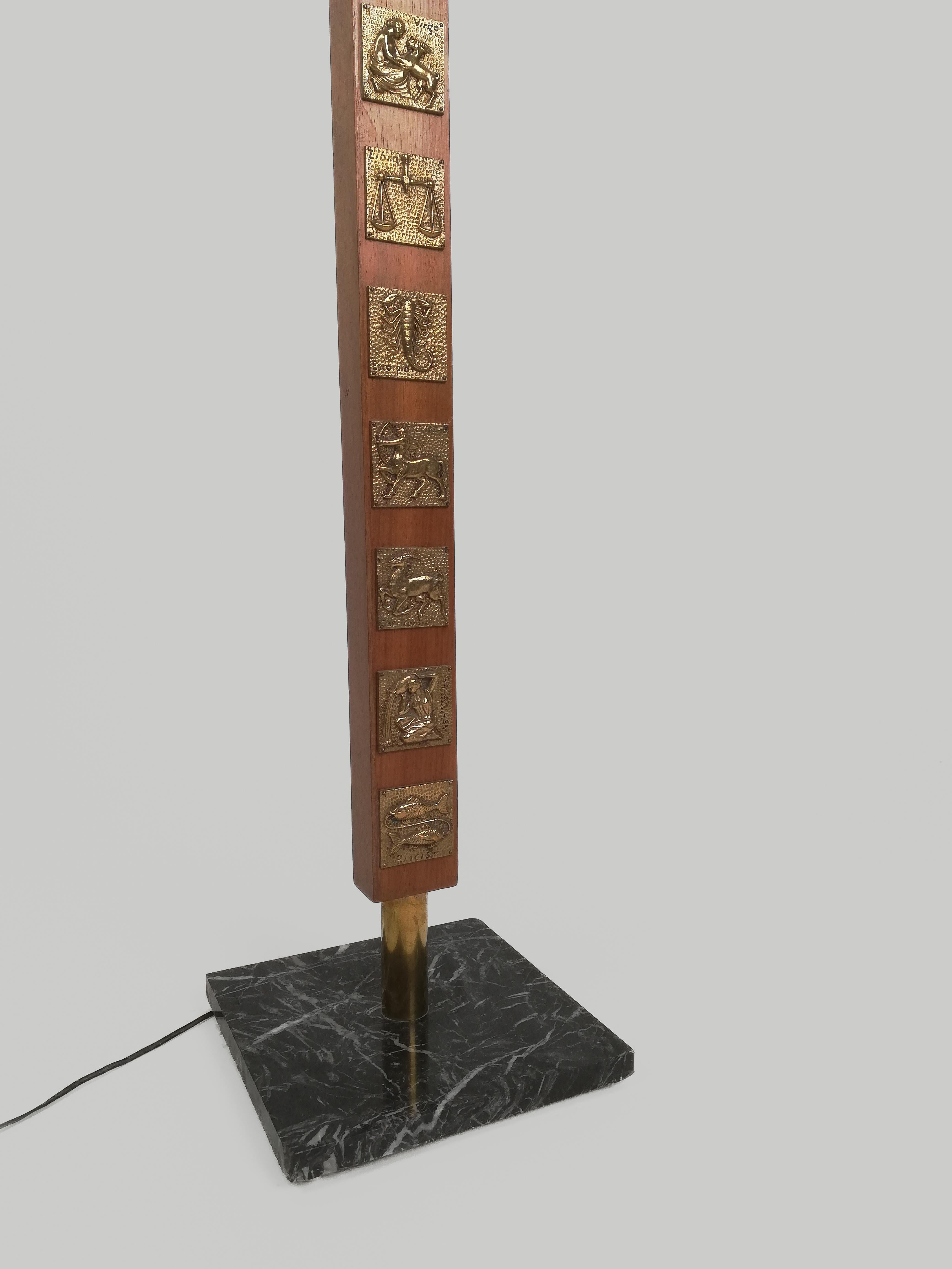 A midcentury floor lamp probably made in Italy between the 1960s and the 1970s.
The solid wood structure is decorated with 12 gilded tiles depicting the zodiac signs.
The decorative theme and the style of the decoration recall the productions of