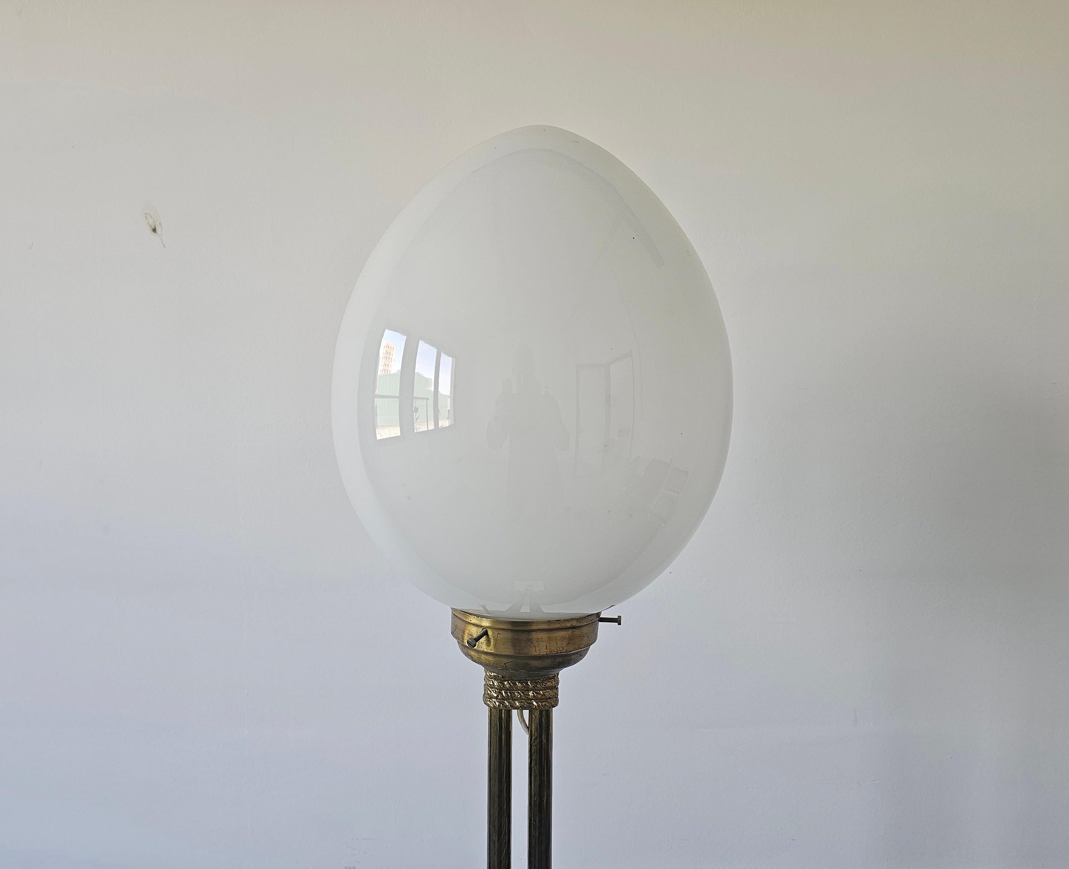 En este anuncio encontrarás una impresionante lámpara de pie Mid Century Modern. Tiene un soporte de latón, una base de mármol y una pantalla de cristal opalino con forma de huevo. Tiene una sola bombilla, modelo E27 o la bombilla equivalente con