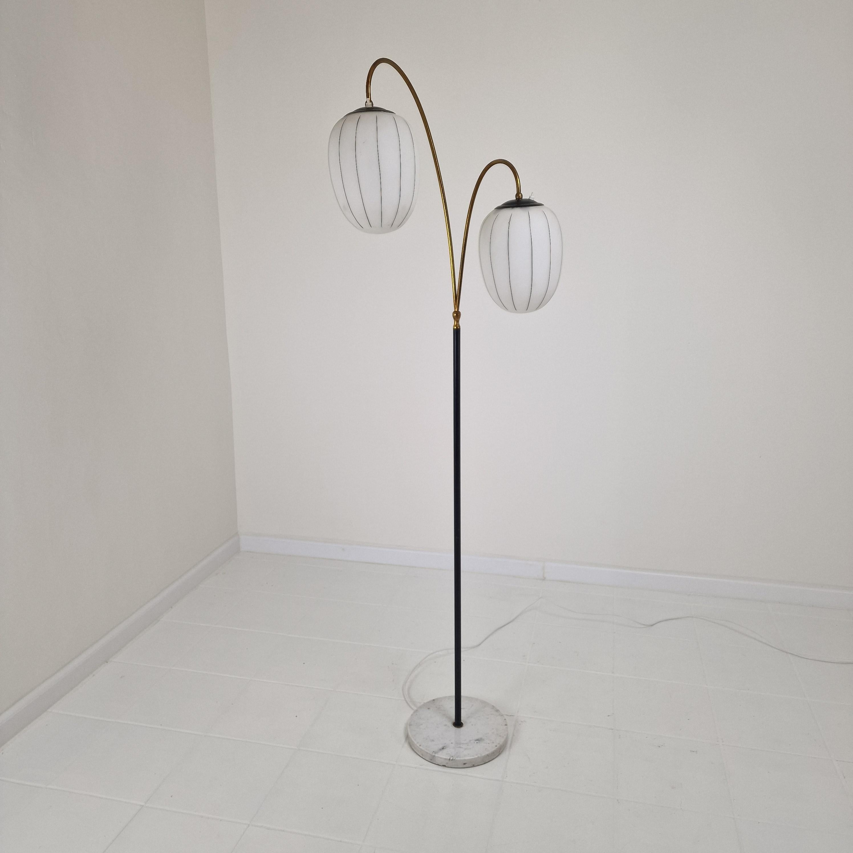 Absolutely stunning and very rare Italian floor lamp, fabricated in the early 60's.

It has a black lacquered steel leg with a round marble base.
The two brass arms are holding the oval opaline glass shades.

It could be a Stilnovo lamp, but it is