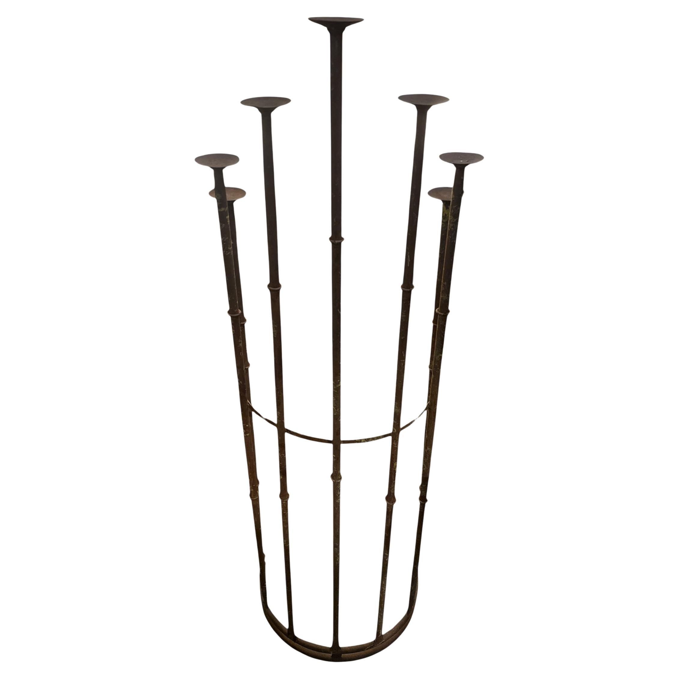 Portacandele in ferro battuto da terra del Mid-Century - Questo portacandele in ferro battuto, realizzato a mano, è un pezzo scultoreo di grande impatto, caratterizzato da sette bracci rialzati di diverse altezze, che conferisce un audace tocco