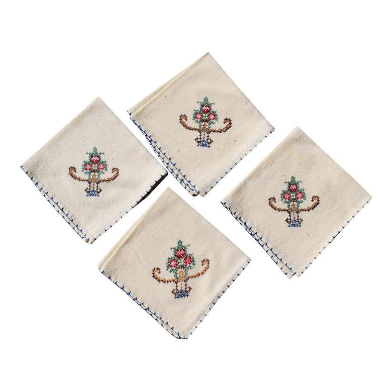 Un ensemble de quatre serviettes de table crème avec un motif floral de chinoiserie cousu à la main. Chaque serviette est de couleur crème, avec un motif floral de chinoiserie cousu à la main dans le coin. La bordure est décorée de longs points