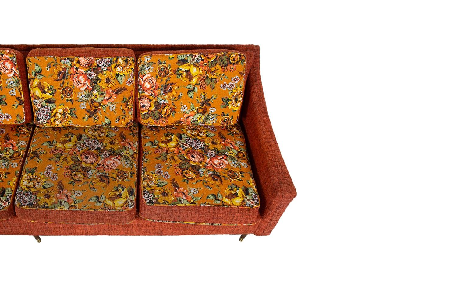 A very attractive long, Floral four-seater upholstered sofa. Features original floral upholstery, four removable seat cushions and back cushions.  The back and clean modern lines give this sofa a sleek silhouette. Resting over distinctive walnut