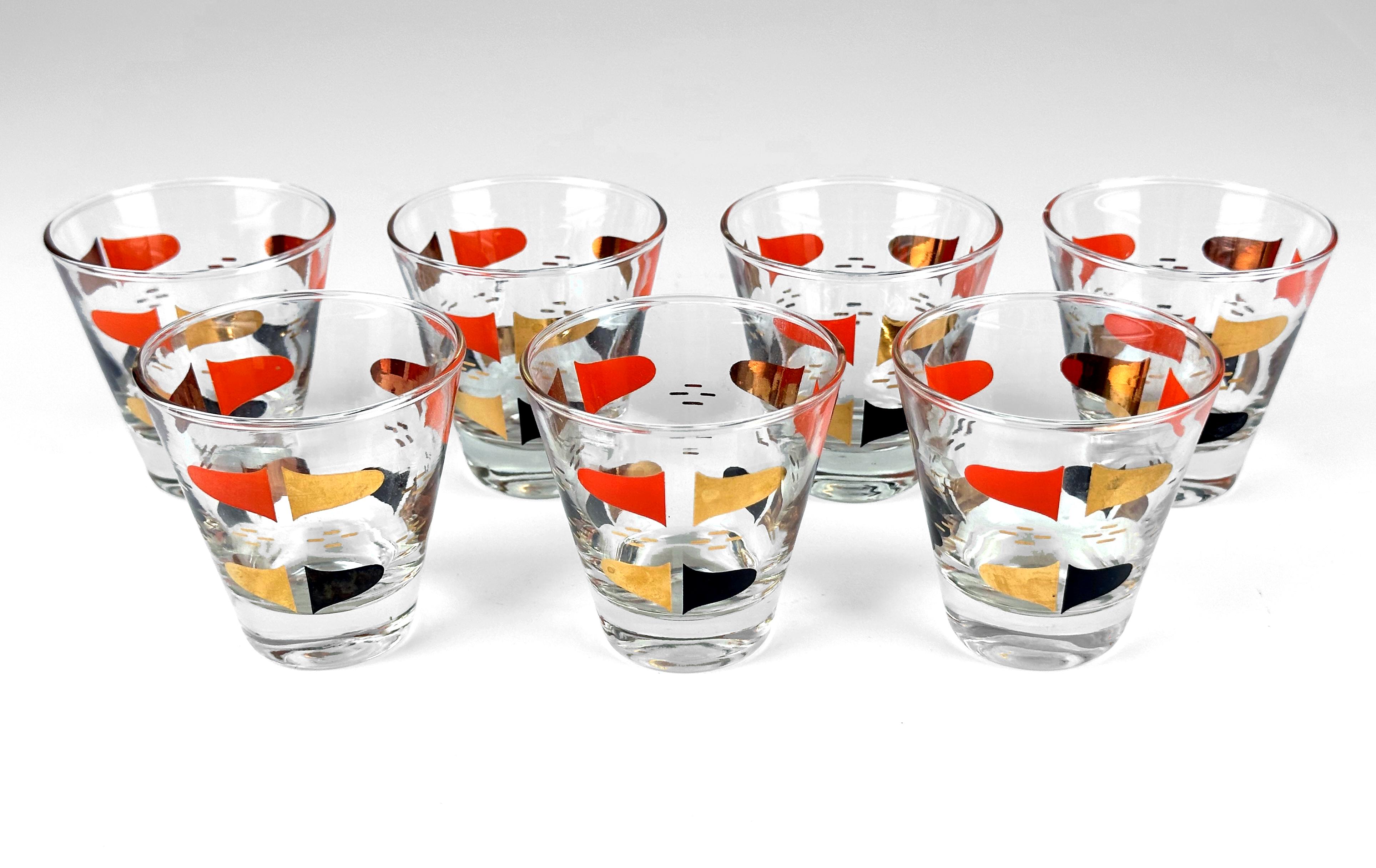 Elevate your vintage barware collection with this rare set of 7 Mid-Century Modern shot glasses by Anchor Hocking. Featuring a bold Florentine graphic in red orange, black, and gleaming gold leaf, these single shot glasses are a stunning example of