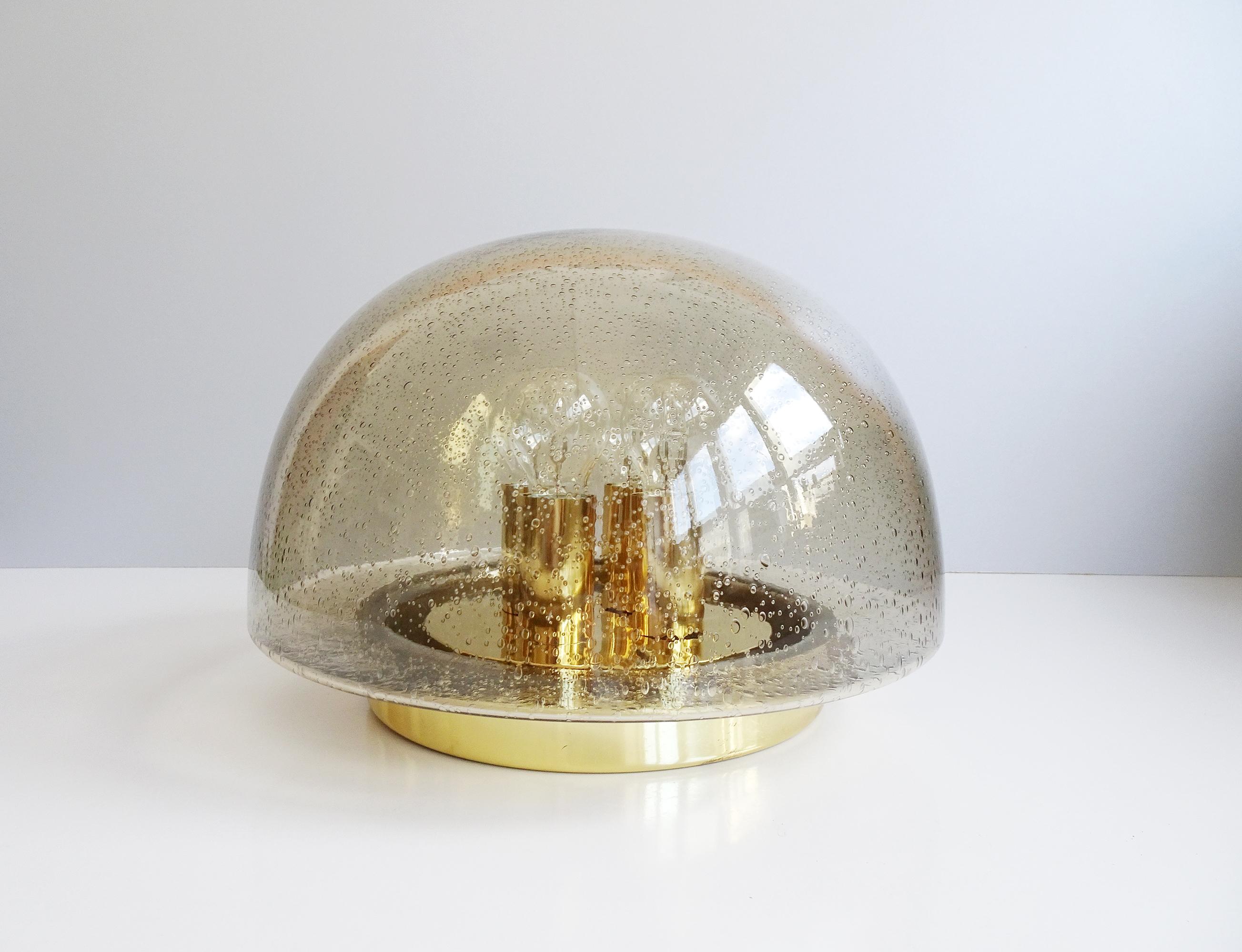 This mushroom-shaped ceiling lamp was manufactured by Glashütte Limburg in the 1960s / 1970s. The amber glass shade with air pockets is a great contrast to the brass base in gold. The air inclusions create a special play of light.

Lamp socket for