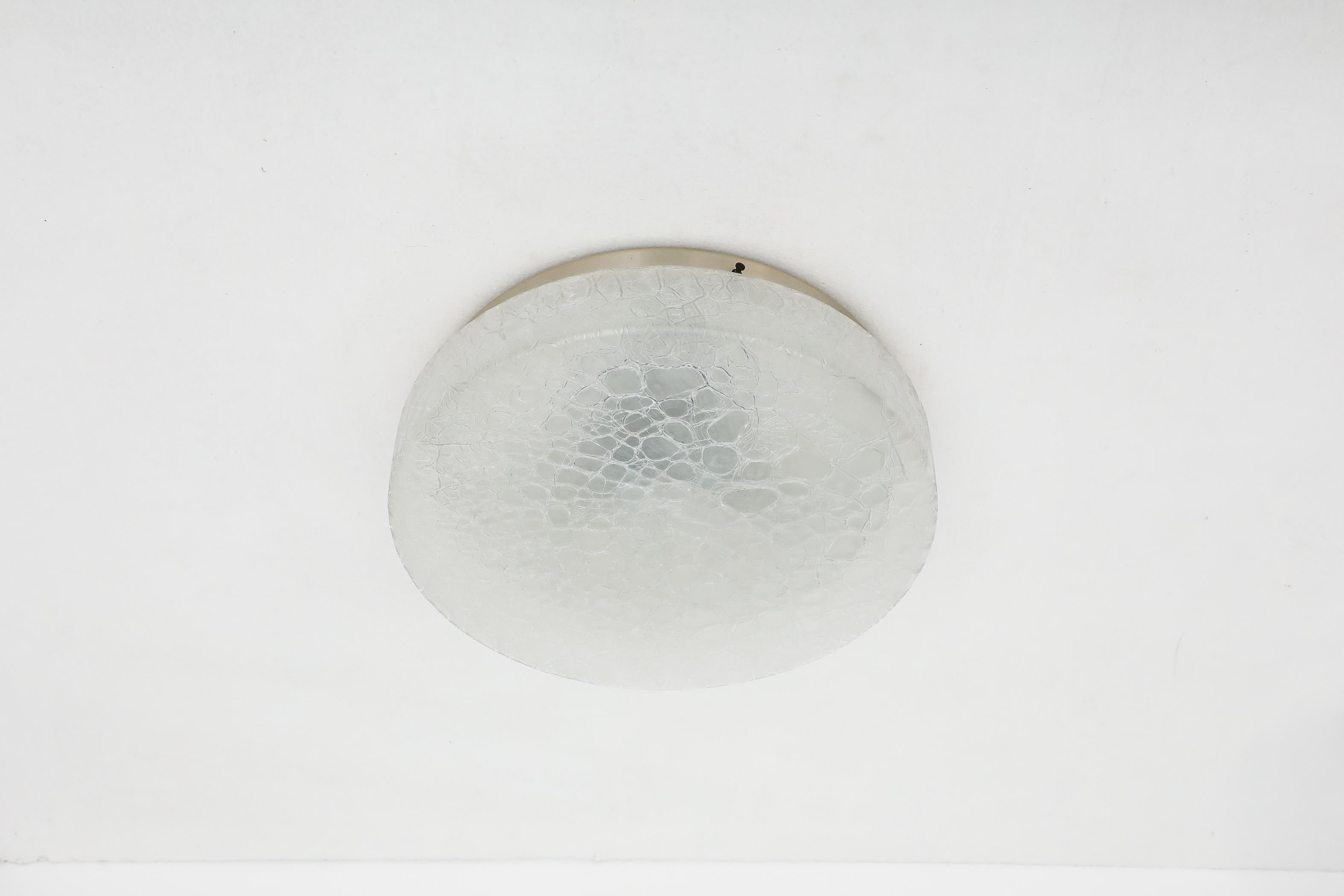 Mid-Century round flush mount textured glass sconce ceiling light by Doria Leuchten with light gold toned base. In original condition with visible wear consistent with its age and use. This lamp is hardwired and takes 3a medium base E26/E27 bulbs,