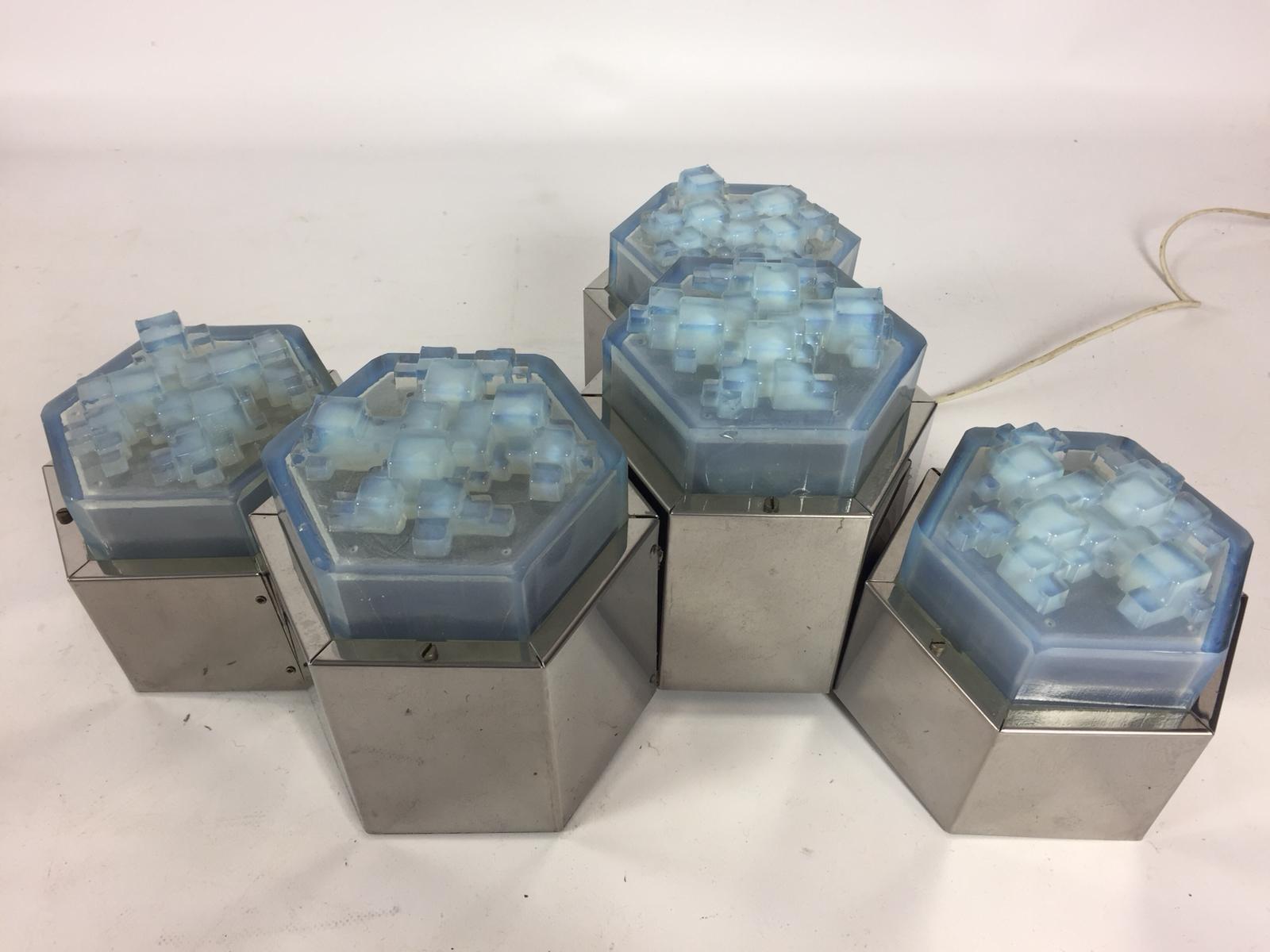 Superbes montures encastrées en verre Poliarte et hexagone chromé. Le verre bleu présente un détail géométrique tridimensionnel. Fixation en chrome avec un peu de patine. Nouvellement reconnecté. Vendu par lot de 5 avec une hauteur différente. Peut