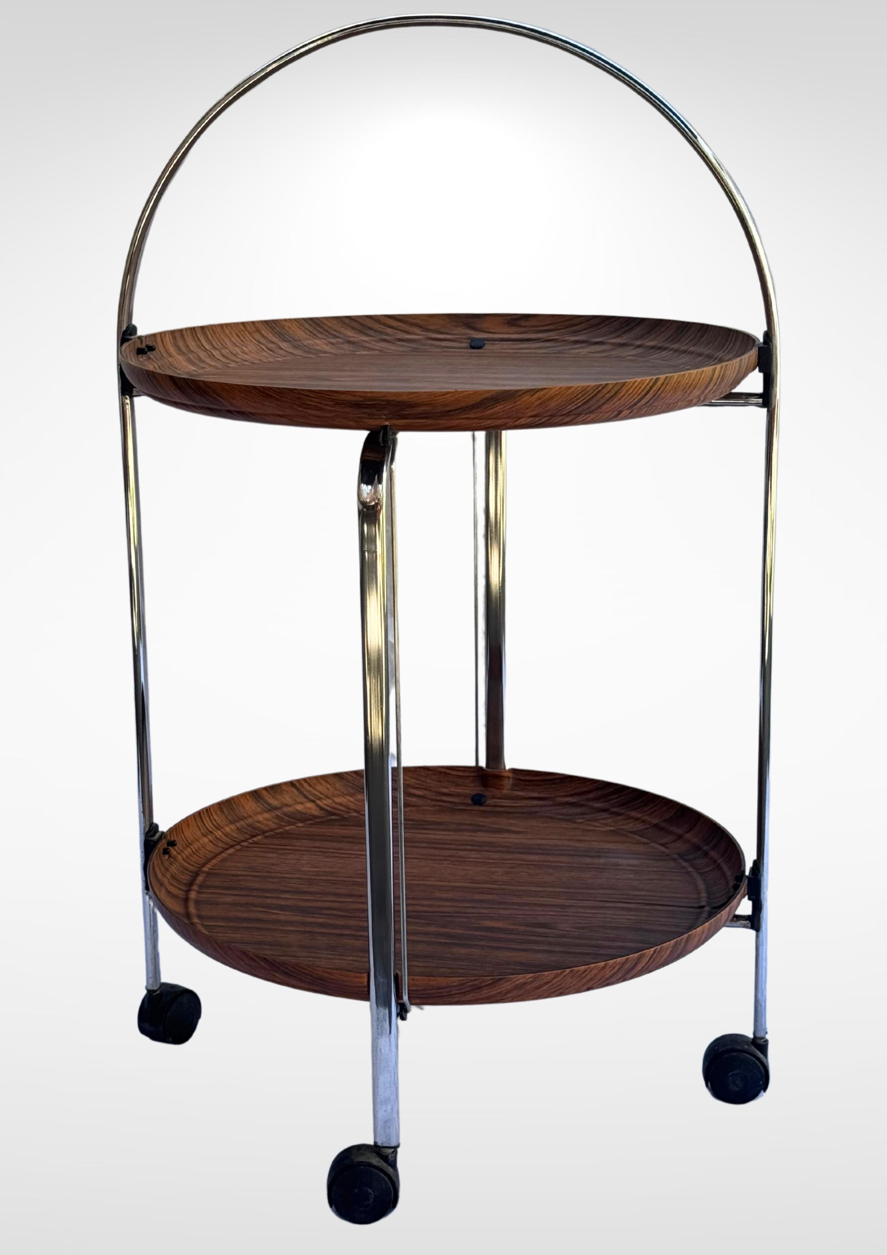 1960s metamorphic bar cart tea trolley in the manner of Nils Trautner for Ary Nybro Sweden.
Chromed steel structure with detachable formica rosewood trays.
Glides on 4 wheeled feet.
In excellent vintage condition.
All chromed surface without rust.