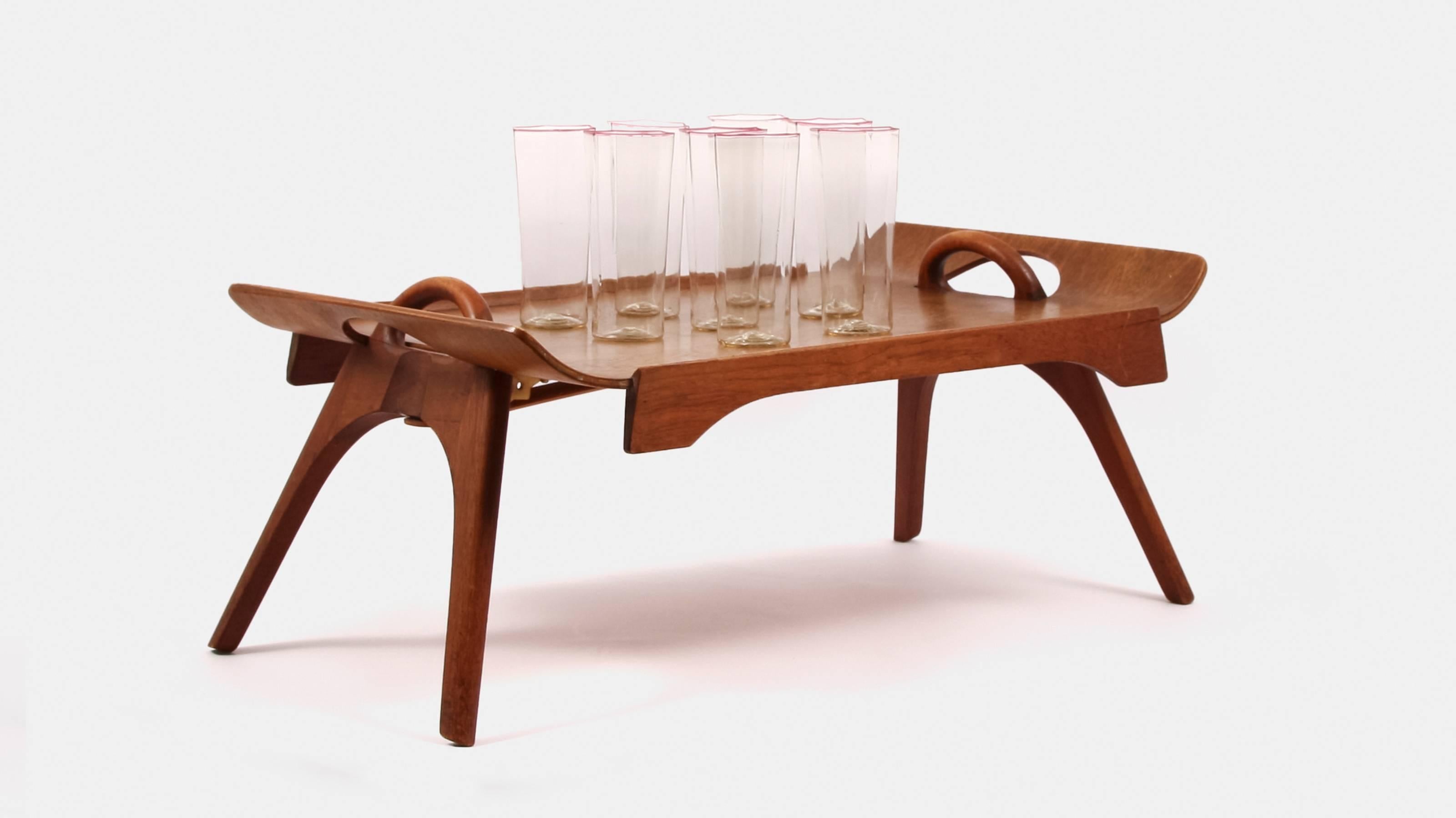 An unusual midcentury drinks tray that has foldable sides with tapered legs.