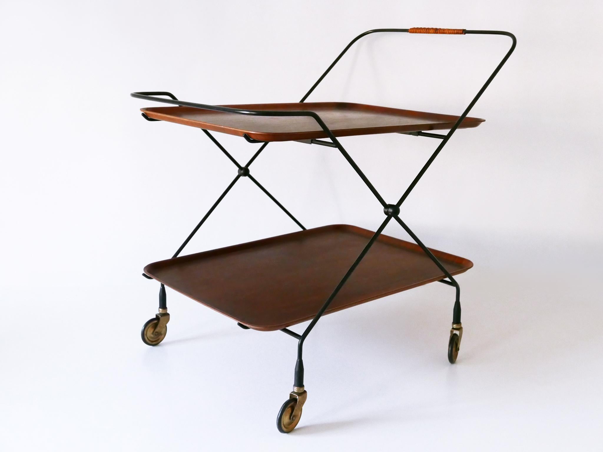 Étonnant et élégant chariot de bar pliant ou chariot à thé de style Mid-Century Modern avec des détails élégants et deux plateaux de service amovibles en teck. Conçu par Paul Nagel pour JIE Gantofta, Suède, années 1960. 

Réalisé en métal émaillé