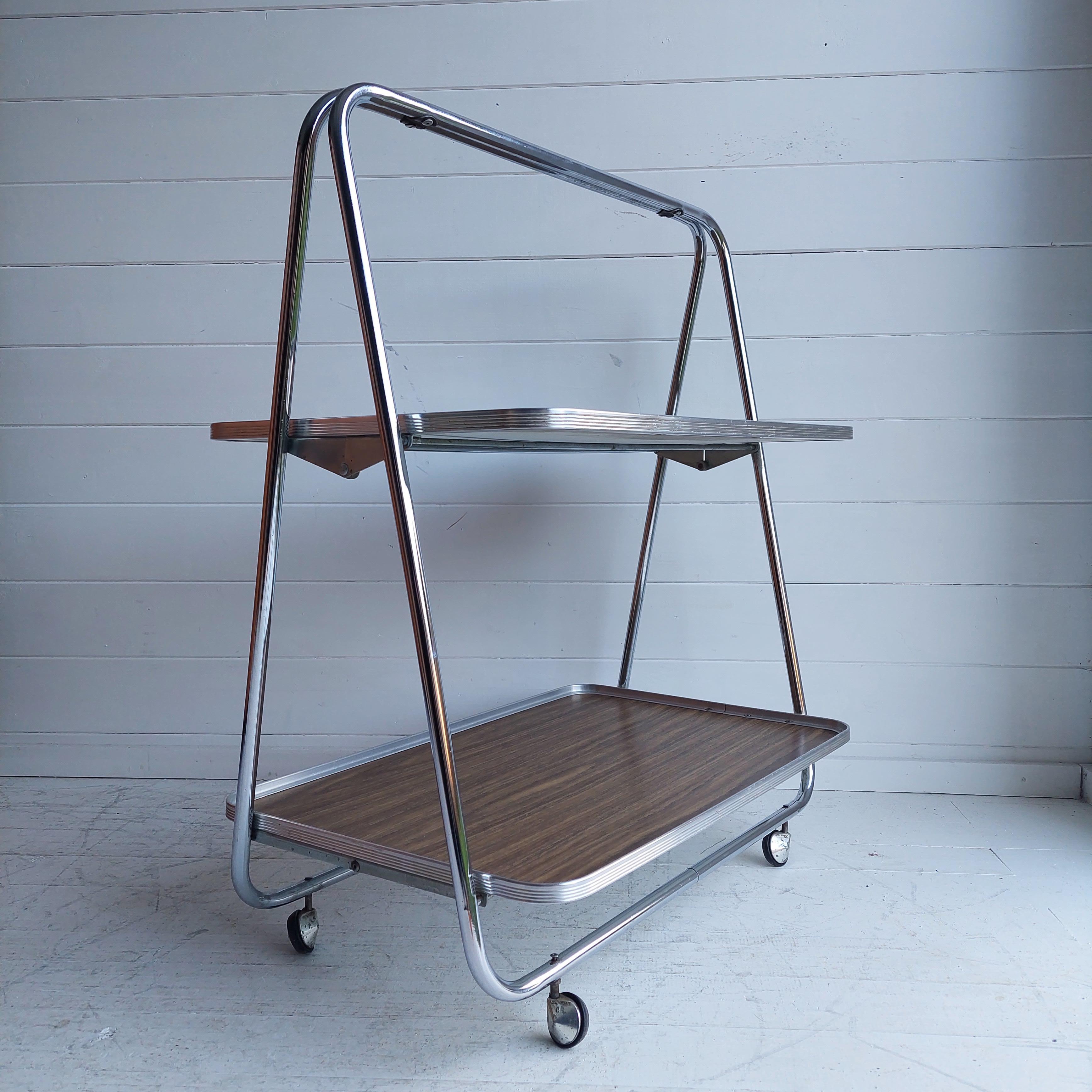 A vintage folding drinks bar cart / tea & cake serving trolley or a portable music stand.
Manufactured in england under Italian Robex influence 1970s.

This is a stylistic vintage retro item with stylish design and creative engineering.

Two