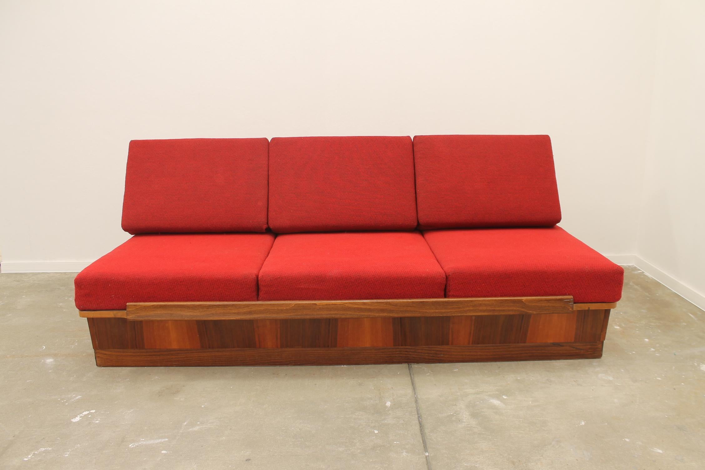 Midcentury folding sofabed, made by Mier company in the former Czechoslovakia in the 1960s. This sofa features a wooden structure that is veneered in walnut. The sofa is in very good vintage condition, showing slight signs of age and using.
