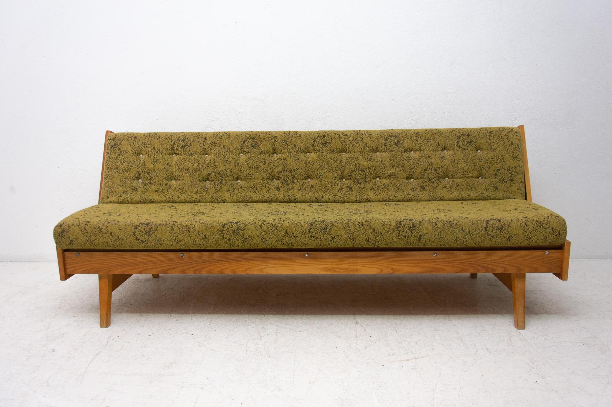 Midcentury sofa bed, made in the former Czechoslovakia in the 1960s. This sofa features a wooden structure that is veneered in oak. The sofa is in very good original condition, shows slight signs of age and using.

Measures: Unfolded 195 × 75 cm.