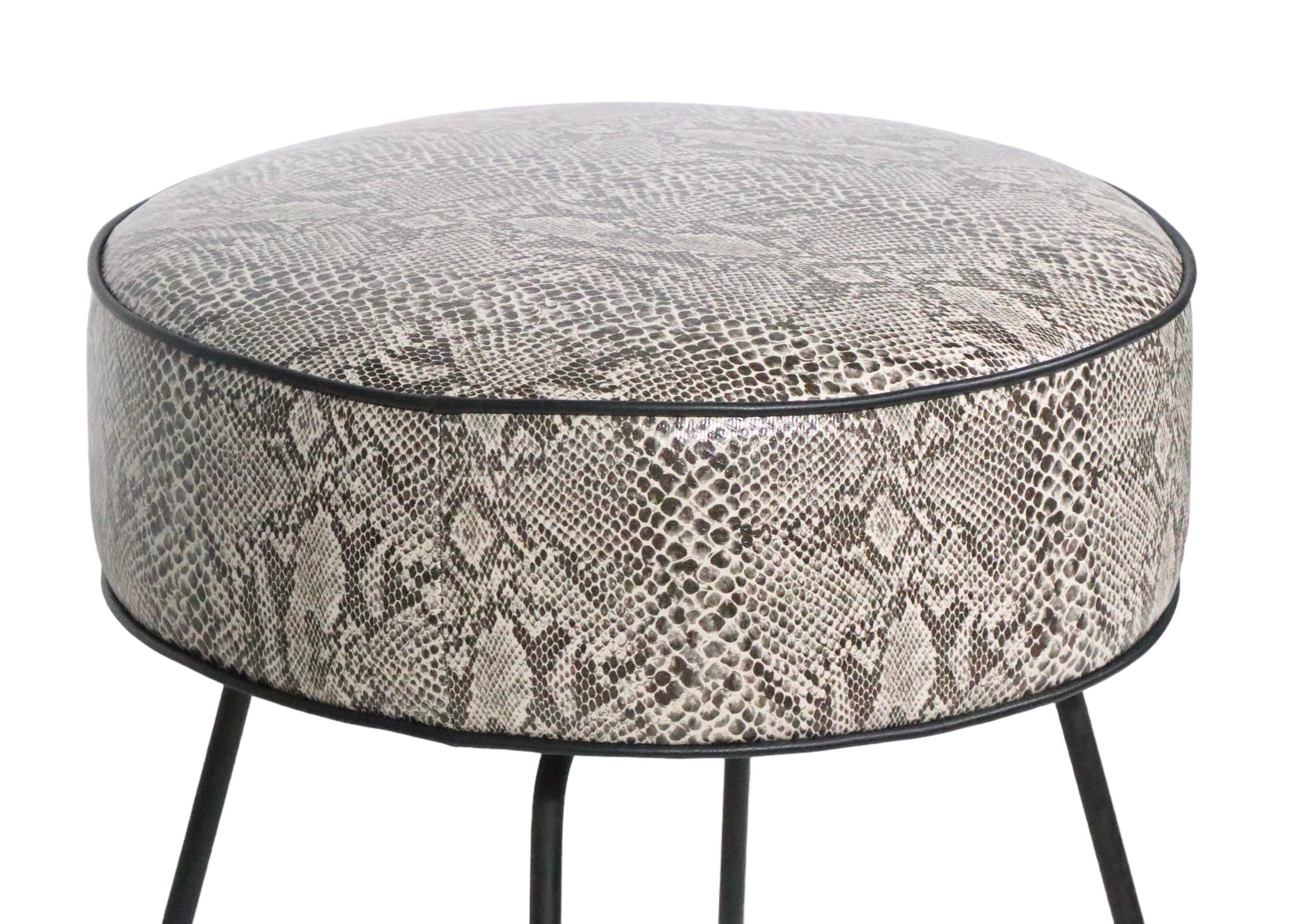 Voguish chic Mid Century, Hollywood Regency style foot stool, ottoman, pouf newly reupholstered in faux python black, gray and white vinyl with black leather piping, on black wrought iron legs. This stylish stool is in excellent clean, ready to use