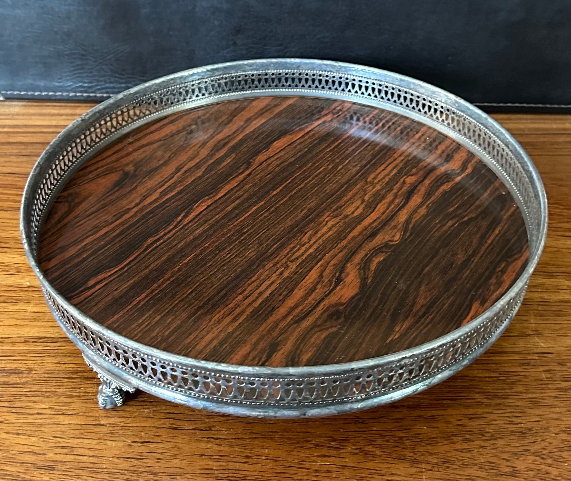 A nice mid-century rosewood Formica footed serving tray with silver plate edge by Sheffield Silver Co., circa 1970s. The tray is in good vintage condition and measures 12.5