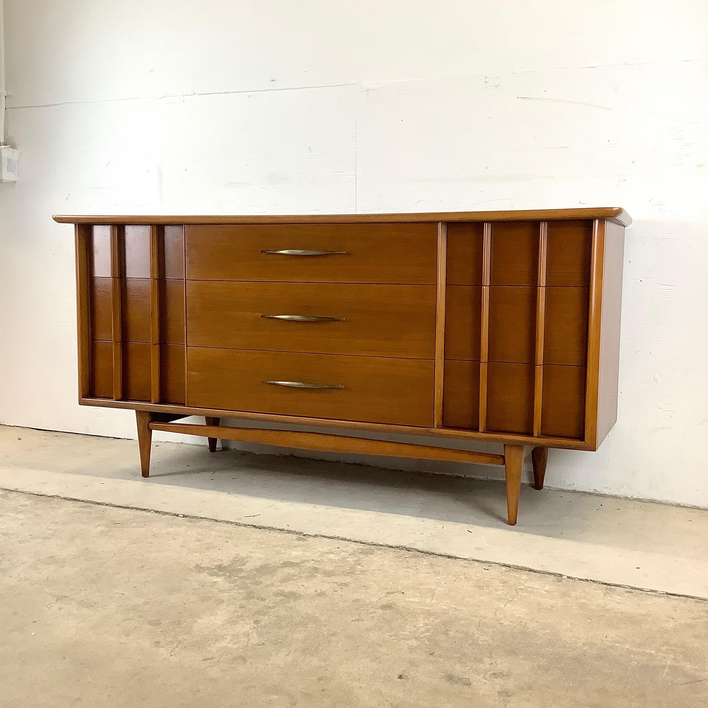 This stylish vintage walnut bedroom dresser from mid-century manufacturer Kent Coffey is from their highly sought after Foreteller line. Unique sculptural drawer pulls, tapered hardwood legs, wide brass center pulls, and clean modern lines make this