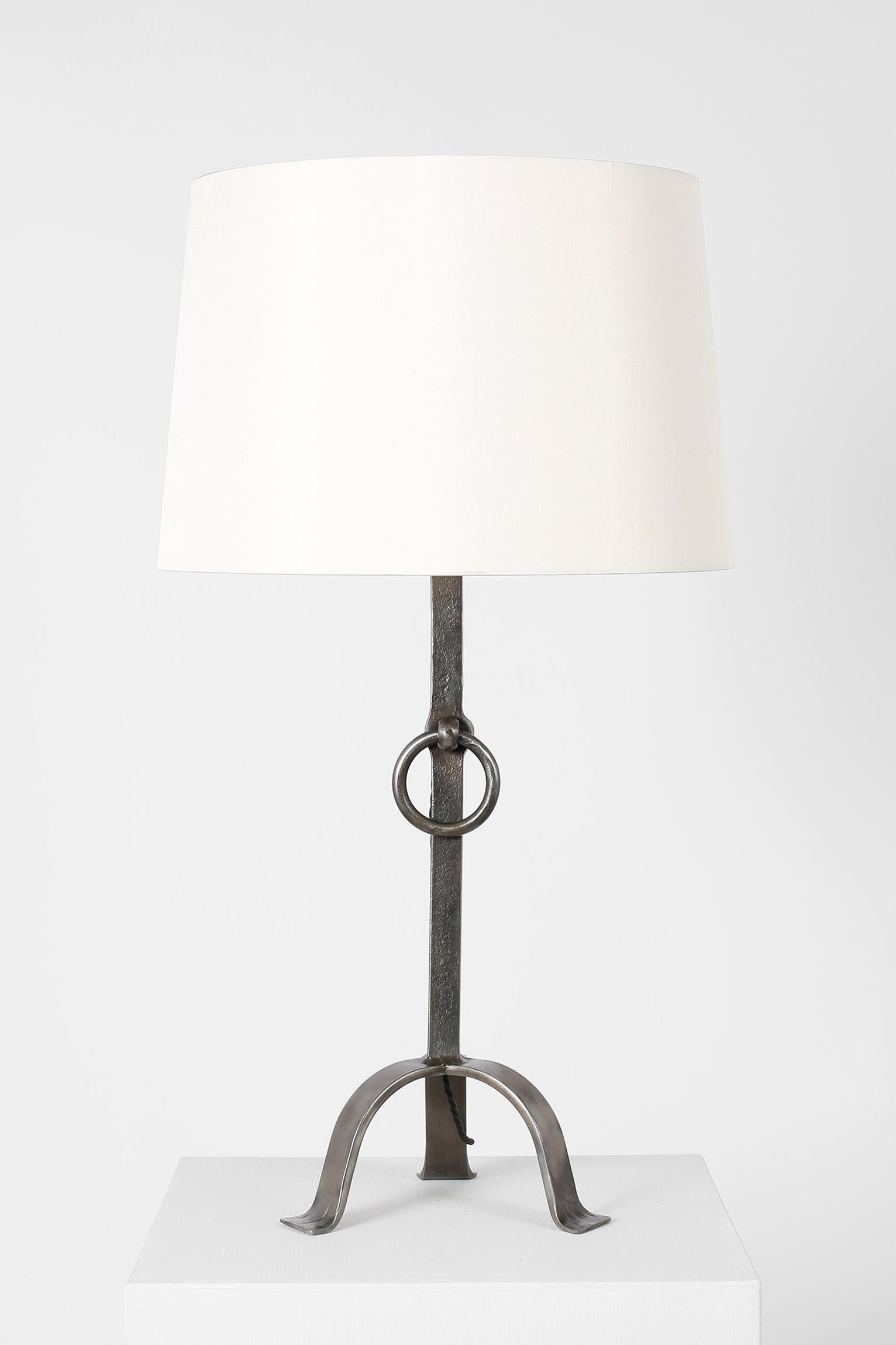 A large forged iron table lamp with decorative ring, in the taste of Les Artisans de Marolles. 
French, circa 1950.
Measures: With the shade: 71 cm high by 40 cm diameter
Lamp base only: 51 cm high by 23 cm diameter.