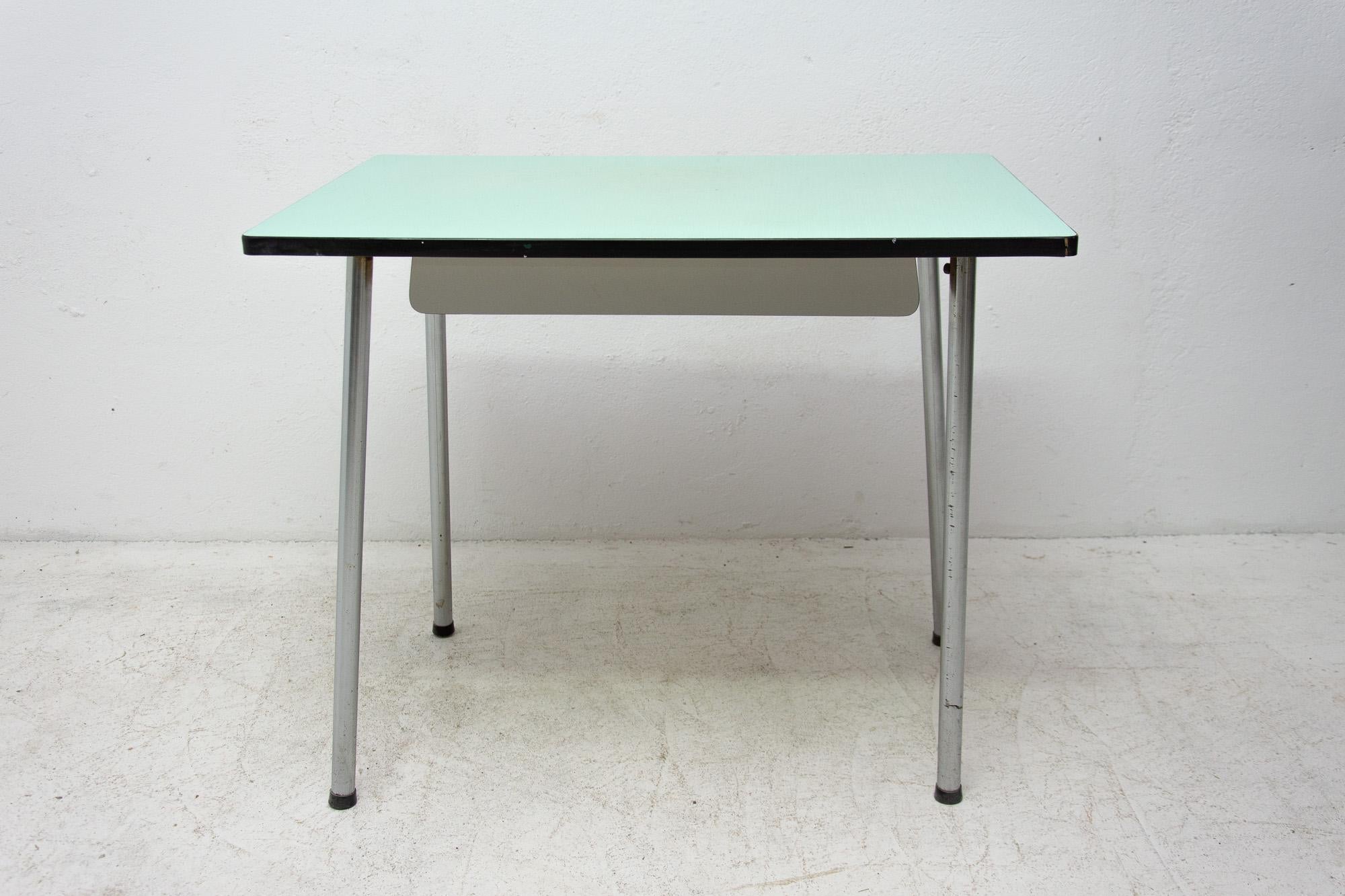 Midcentury writing desk or side table, it features a Formica surface and chromed legs and one-drawer. It was made in Czechoslovakia in the 1960s.

The tabletop is lined with a black plastic strip, there is damage to this strip in several