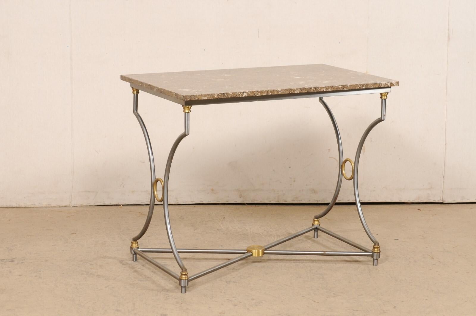 A mid-century American accent table with steel base and fossilized marble top. This American-made table, circa 1960, has a rectangular-shaped fossilized marble top, which is raised upon a steel base. The legs are comprised of a pair of round/slender