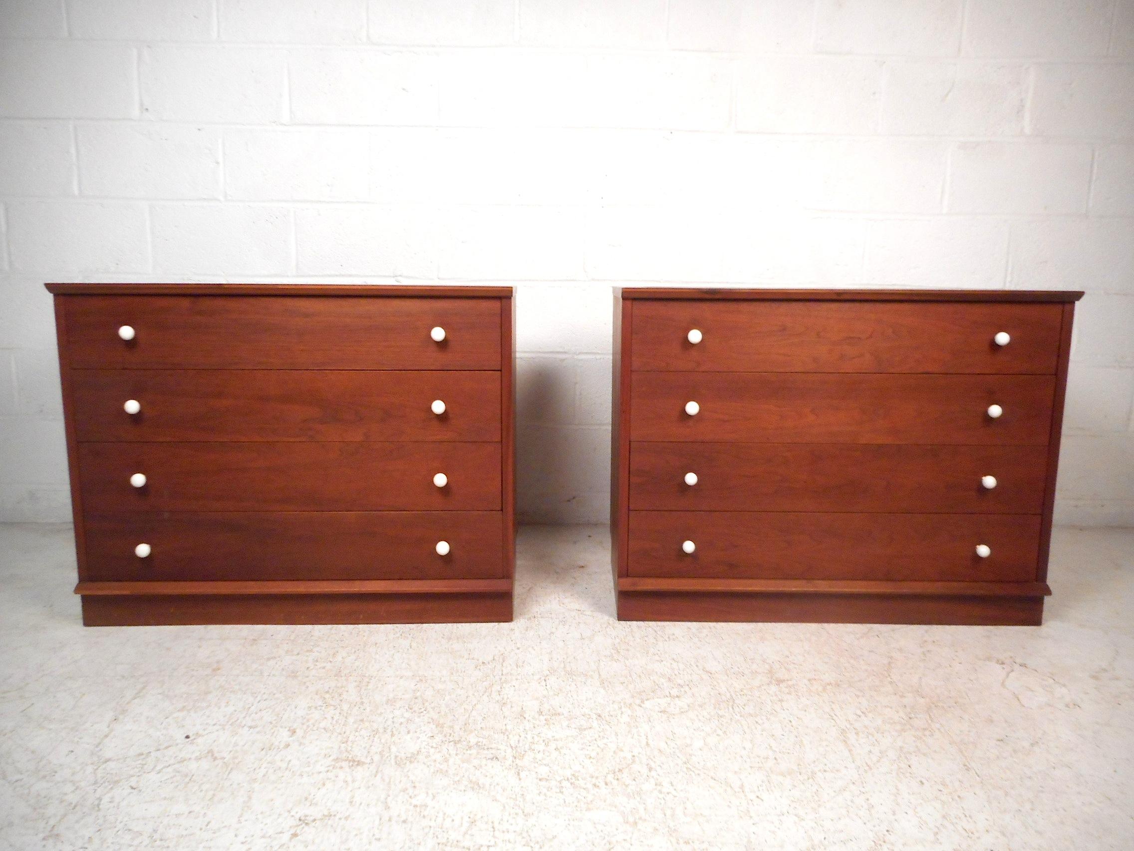 Stylish pair of midcentury dressers. Sturdy construction consisting of finished walnut. Sleek round white drawer pulls. Each piece has four spacious drawers with dovetail-joint construction signifying quality craftsmanship. An impressive addition to